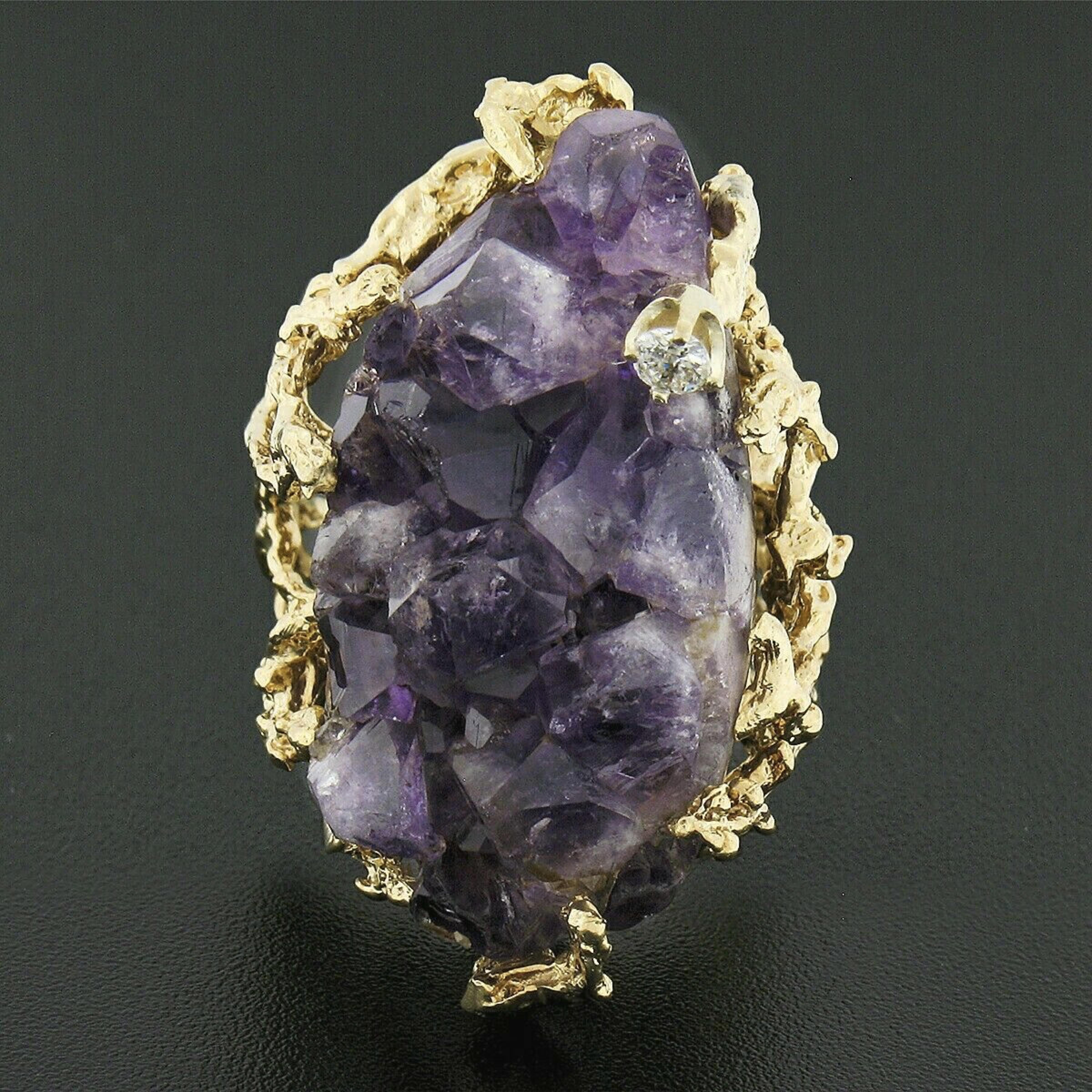 This magnificent vintage cocktail ring is crafted in solid 14k yellow gold and is set with a MASSIVE, rough, uncut amethyst crystal at its center. The incredible stone weighs approximately 30-50 carats, displaying a gorgeous medium to dark purple