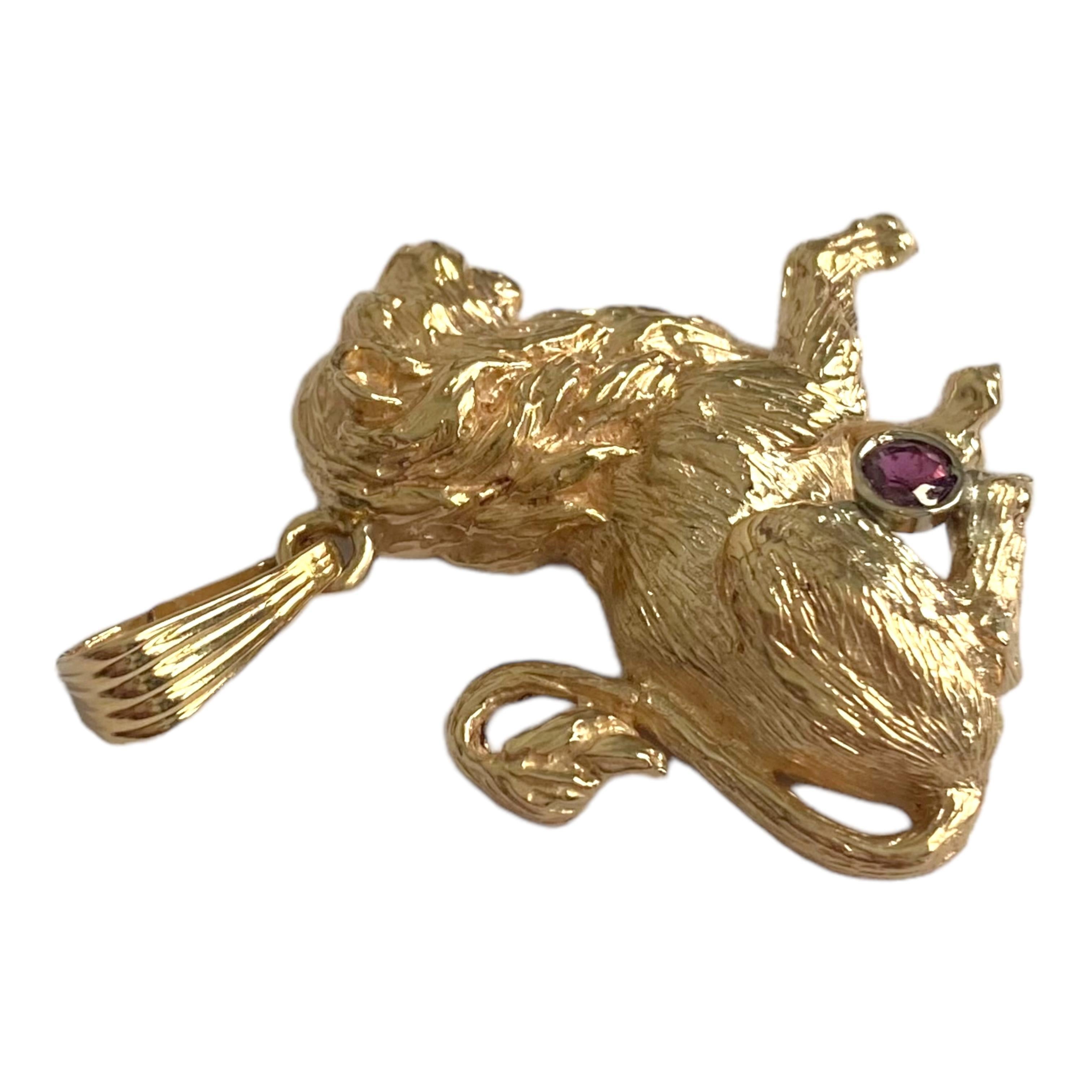Crafted in 14K yellow gold, the pendant features a side image of a sitting lion accented with a round bezel set garnet. Textured finish and large bail. 
Measurements: 40 mm (including bail) x 30 mm W x 5.5 mm D
Weight: 9.7 grams
Marked: 14K