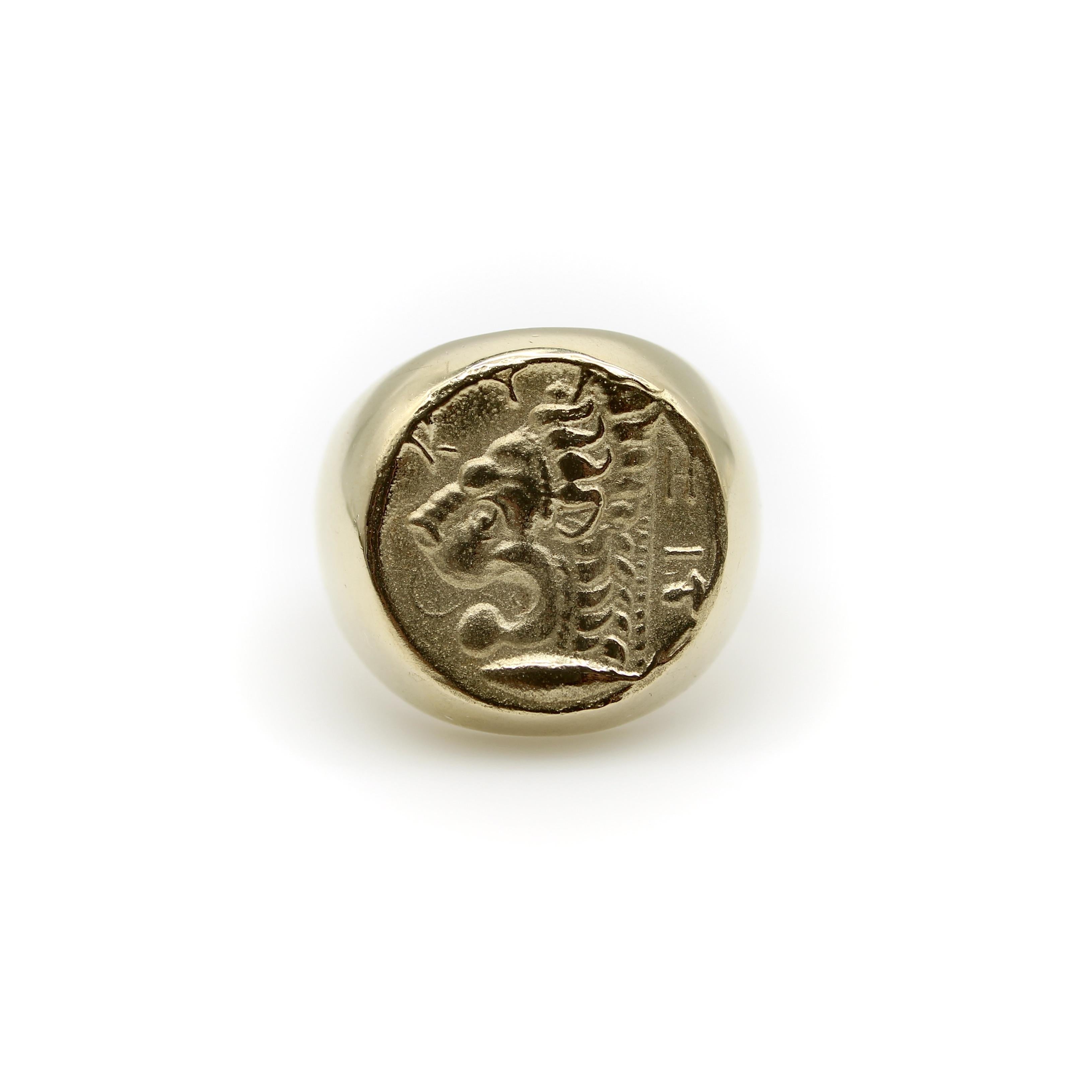 This ring is a 14k gold version of the image of the lion found on the Greek Cyzikos coin that dates to 4th century BC. The image is of the head of a lion above a tuna fish, as though guarding it. Above the lion is Greek lettering K Y and H, with T