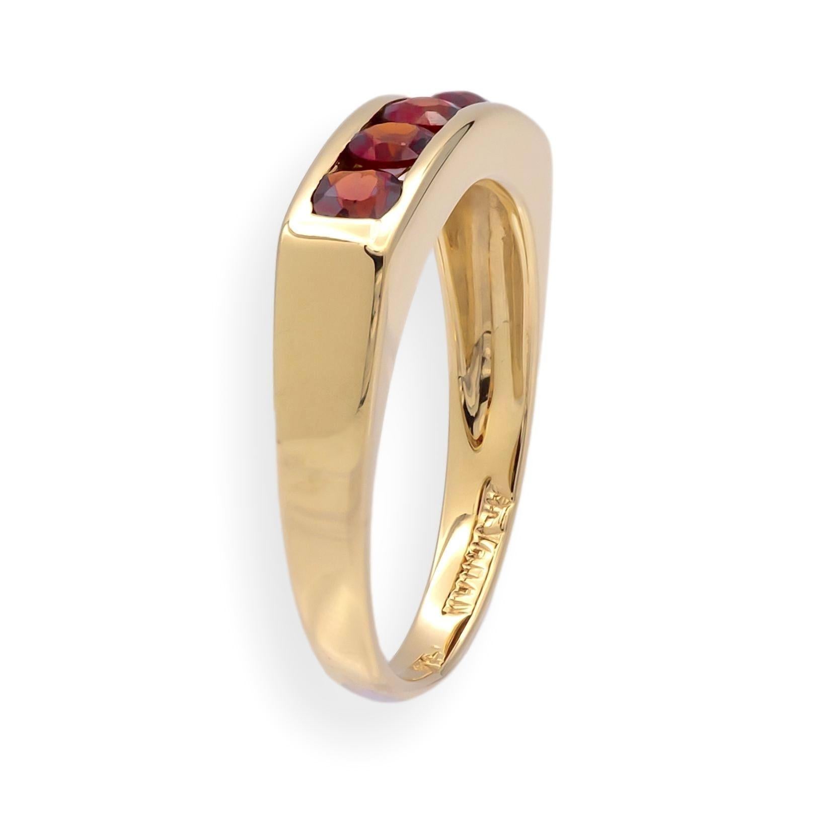 Cette bague vintage du milieu du siècle dernier à cinq pierres en or jaune 14 carats présente un anneau épuré et architectural avec cinq grenats ronds d'un rouge éclatant sertis dans un canal élégant. Le design reflète l'élégance minimale typique