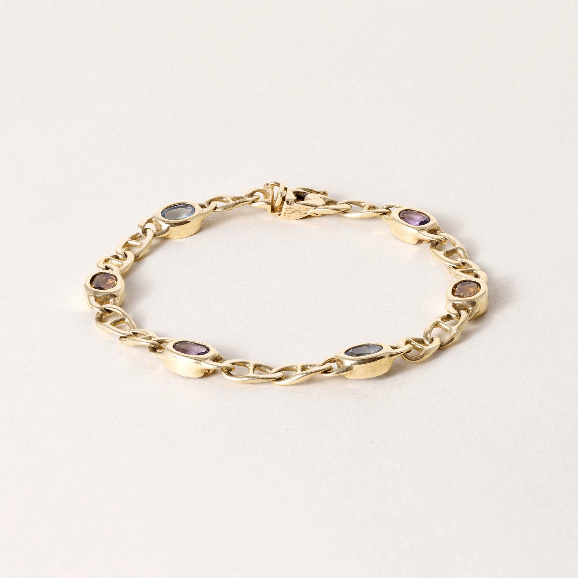 Se trata de una pulsera vintage de eslabones de cadena con varias piedras preciosas en oro amarillo de 14 quilates.
Detalles:

Seis gemas intercambiables de talla ovalada que incluyen amatista, topacio y citrino
Cada bisel engastado en oro amarillo
