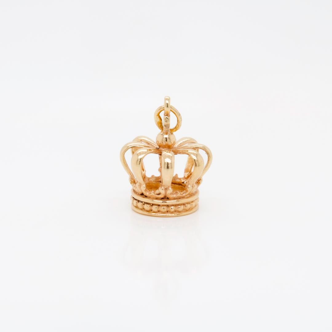 A fine vintage gold charm for a charm bracelet.

In 14k gold. 

In the form of a regal crown in the European style with 8 half-arches supporting a figural cross monde.

With an integral bail and jump ring at the top of the crown's cross.

Simply a