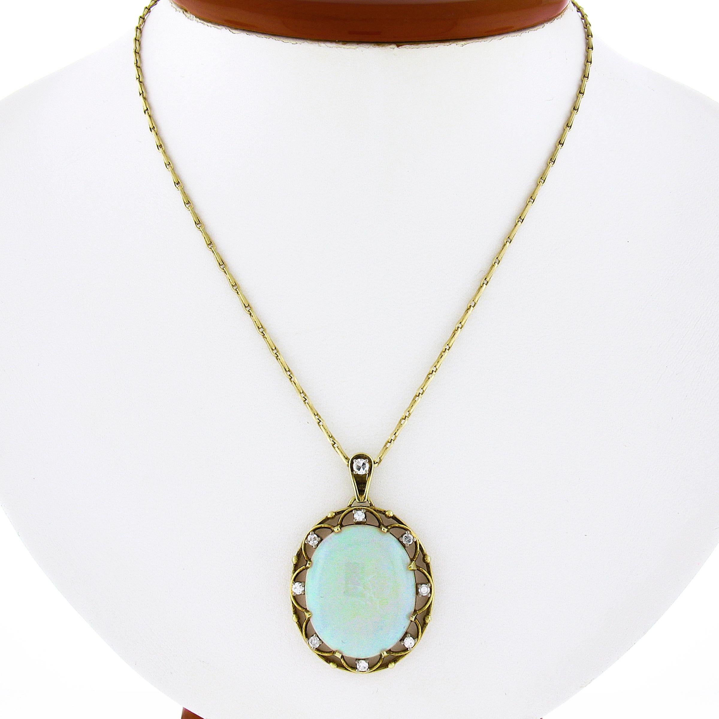 This vintage pendant is crafted in solid 14k yellow gold and features a beautiful open work design. The pendant is prong set with an oval cabochon opal that displays lovely white base color with green, blue and orange play of color throughout. The