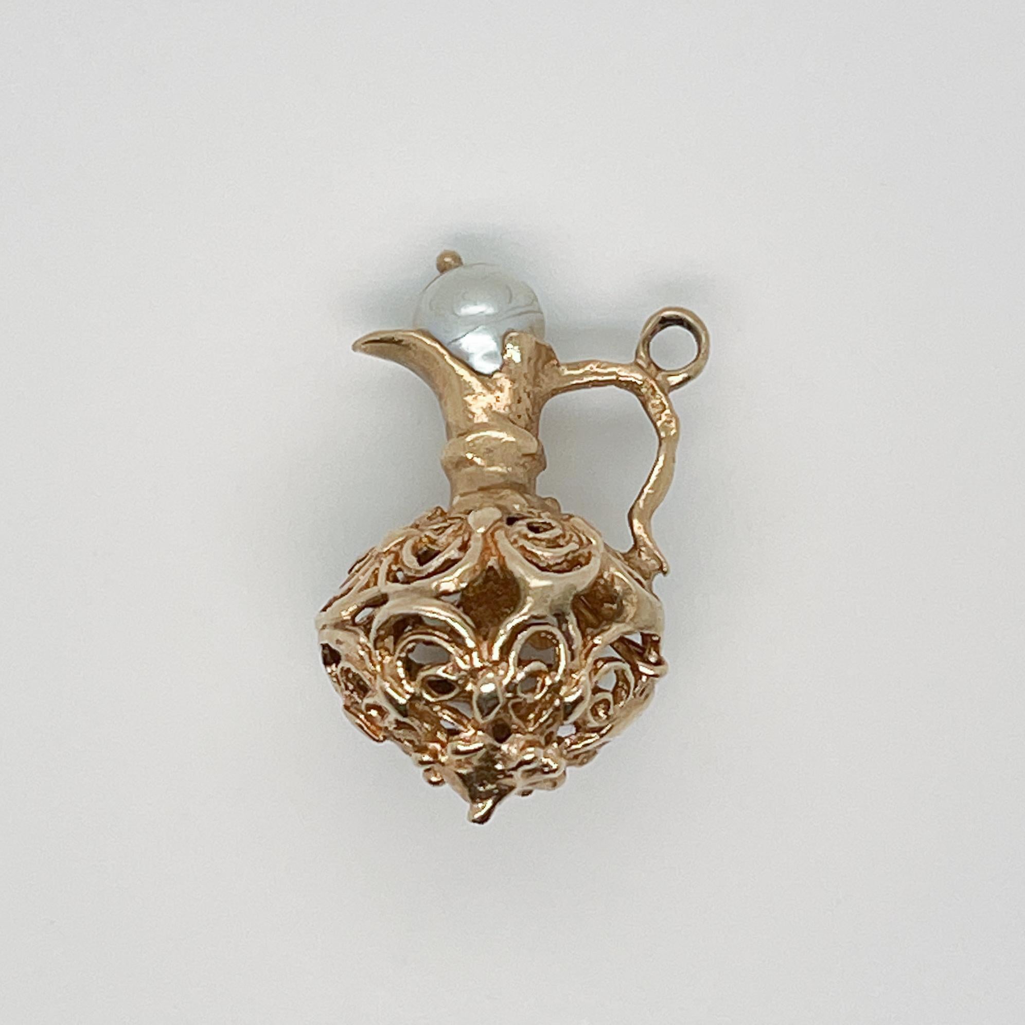 A vintage 14 karat gold charm for a charm bracelet. 

In the form of an intricate filigree pitcher or wine ewer with a pearl stopper.

A rare and terrific charm!

Date:
Mid-20th Century

Overall Condition:
It is in overall good, as-pictured, used