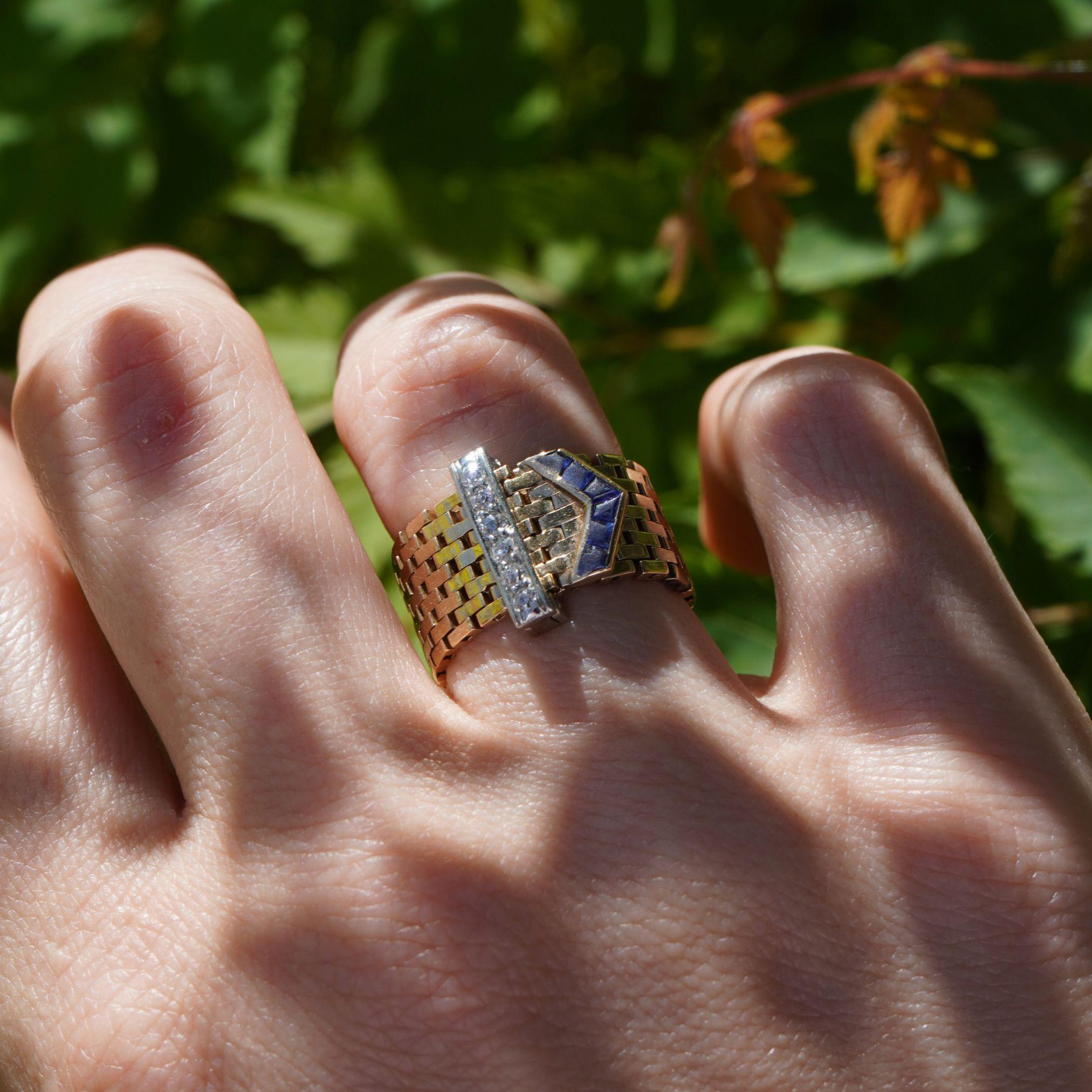 Esempio straordinario di design dell'epoca retrò, questo anello con fibbia del 1940 circa combina funzionalità e fascino visivo. Realizzato in oro giallo 14 ct. con un motivo a fibbia in platino, l'anello presenta una struttura flessibile a maglie