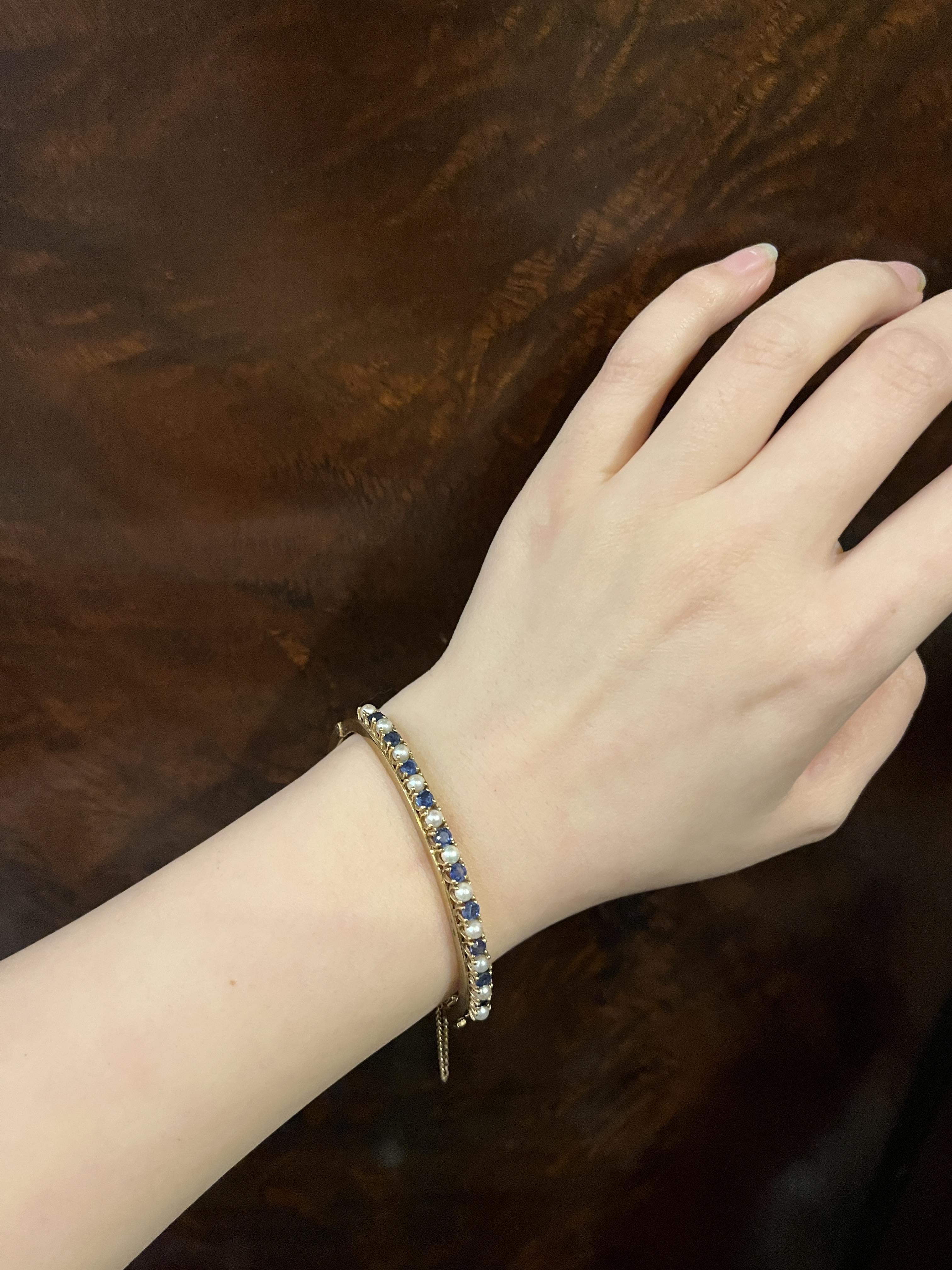 Vintage 14K Gold Sapphire Pearl Bangle Bracelet

Marked: 
14K

Approximate Dimensions: 
16.5 cm (Unclasped Length) 
0.5 cm (Width) 
Approx. 1 carat (Sapphire)  
3.23 mm (Pear)
15.6 grams in weight.