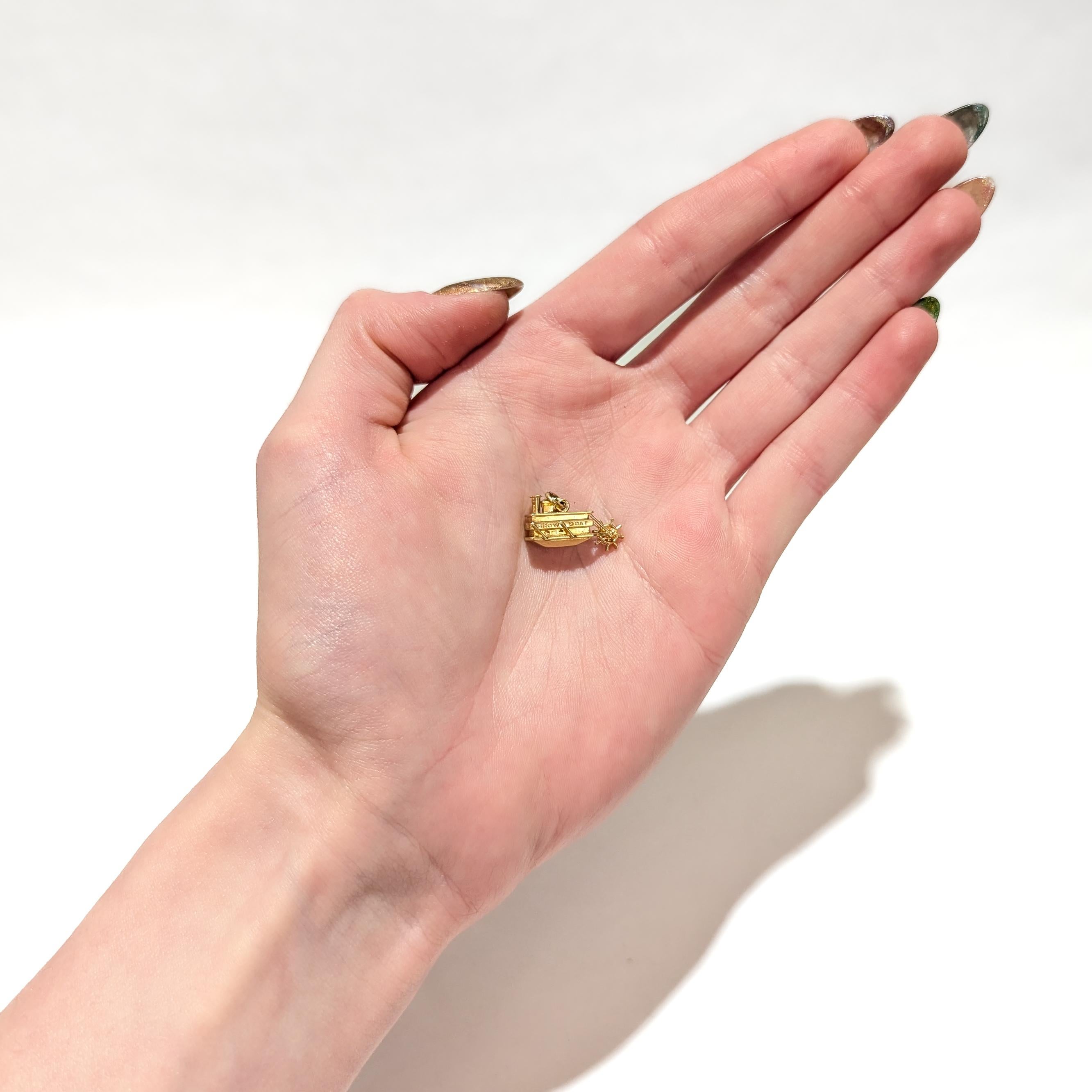 A fine vintage gold charm for a charm bracelet.

In 14 karat yellow gold.

In the form of a paddle steamer boat. The paddlewheel spins freely.

Engraved to one side of the boat with the words 'SHOW BOAT' and to the other side with 'SHOW .OAT'

Fully
