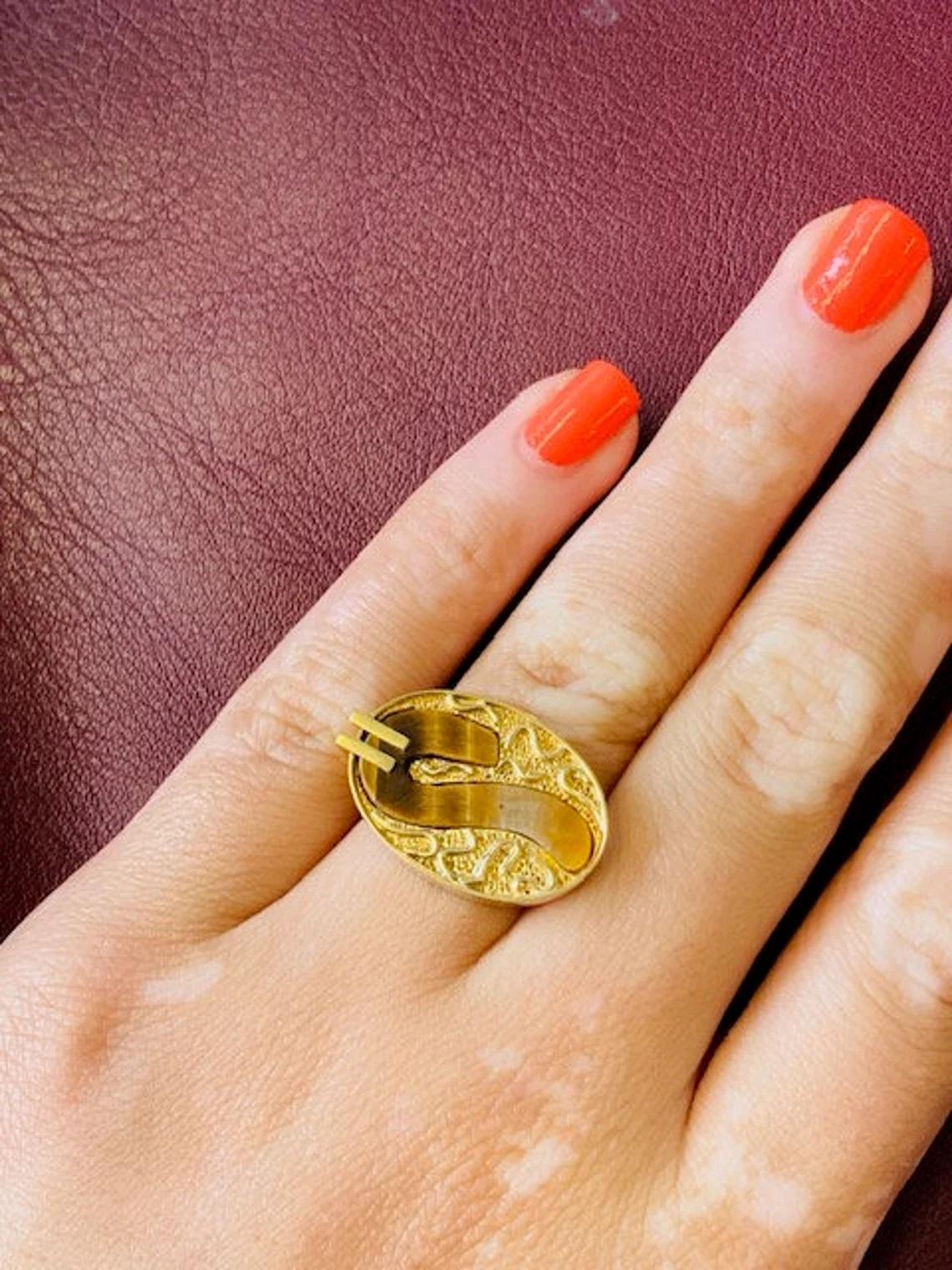 Vintage 14k Gold Tiger's Eye Unisex Siegelring, Einzigartig

Dieser Unisex-Siegelring hat ein einzigartiges, kompliziertes Design mit einem marmorierten Tigerauge in der Mitte. Die Brauntöne in Verbindung mit dem 14-karätigen Gold machen diesen Ring