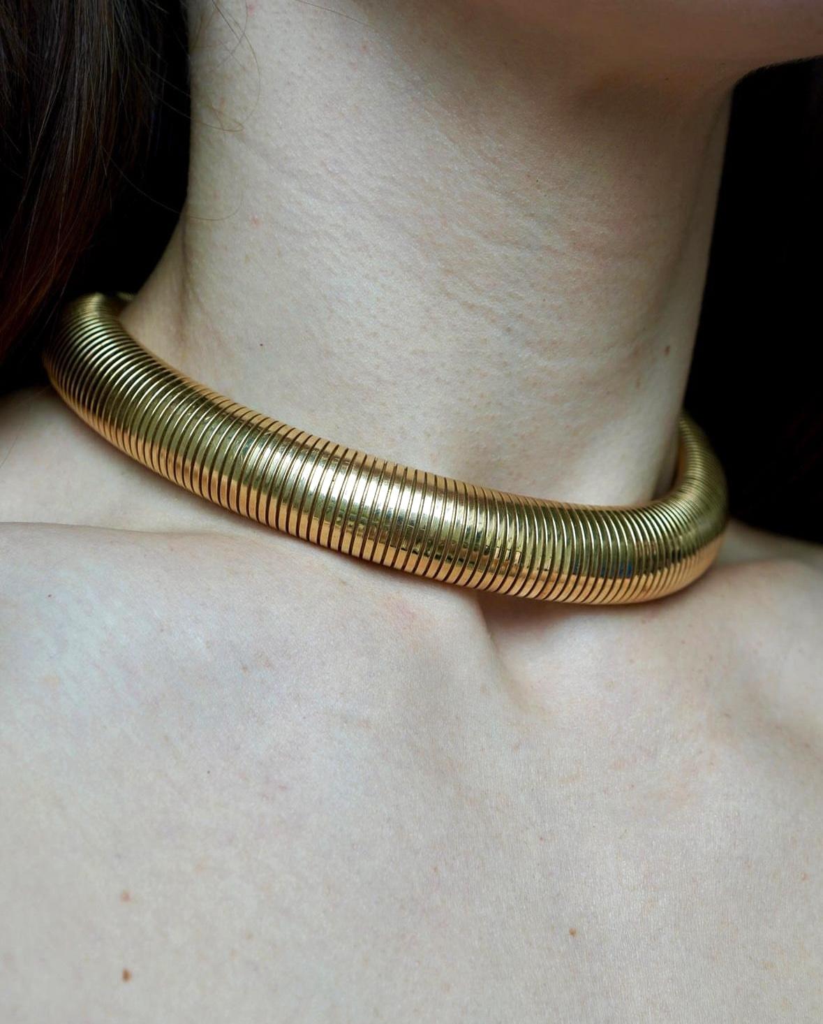Ce collier ras-de-cou vintage en or 14 carats, datant des années 1950, est un exemple classique du design du milieu du siècle. Le collier mesure 15 pouces de long et 5/8 pouces de large, pour un poids substantiel de 114,3 grammes. Le style tubogas,