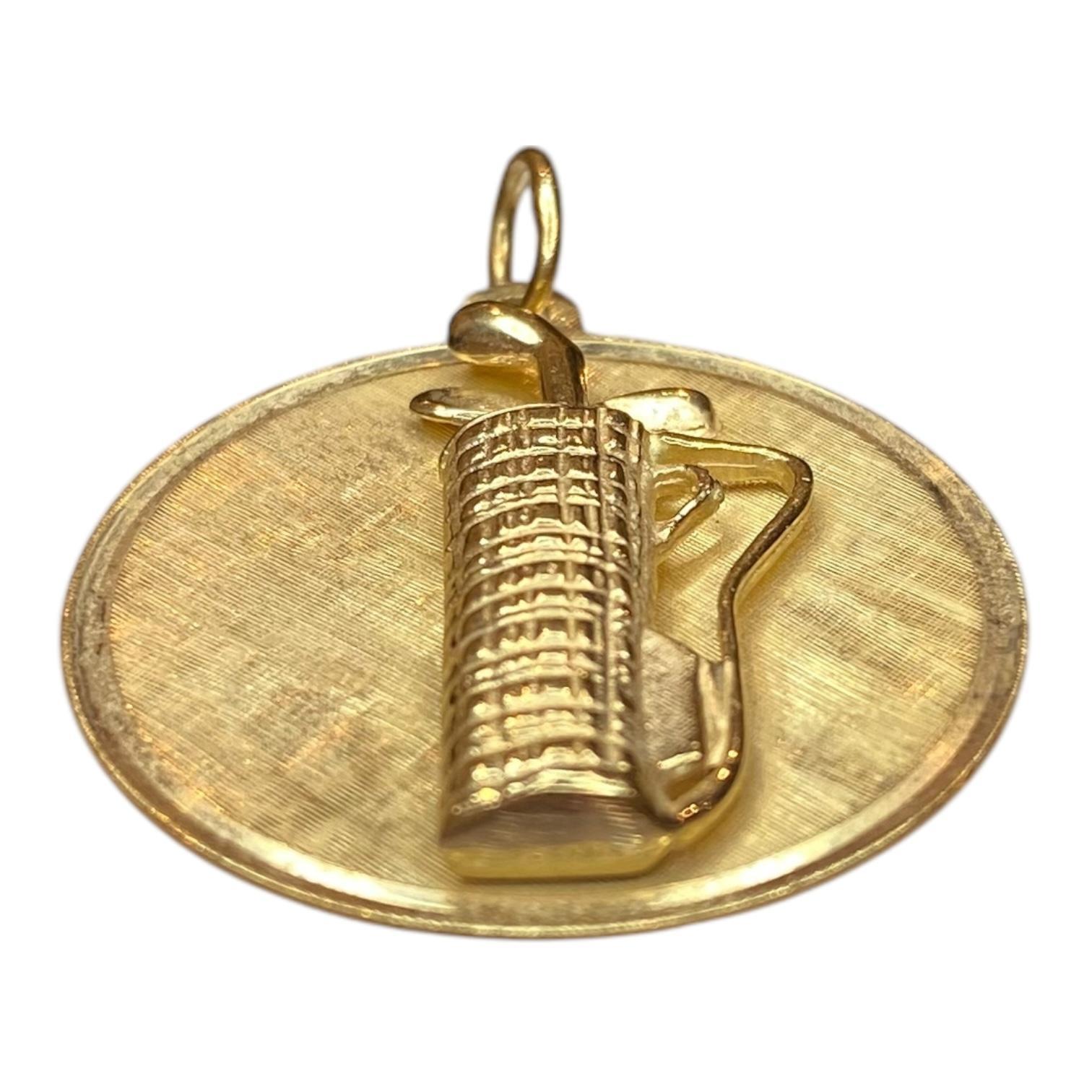 Crafted in 14K yellow gold, the pendant features a raised design with a golf bag and clubs. The piece showcases a textured finish, adding depth and character.
The reverse side is engraved: 