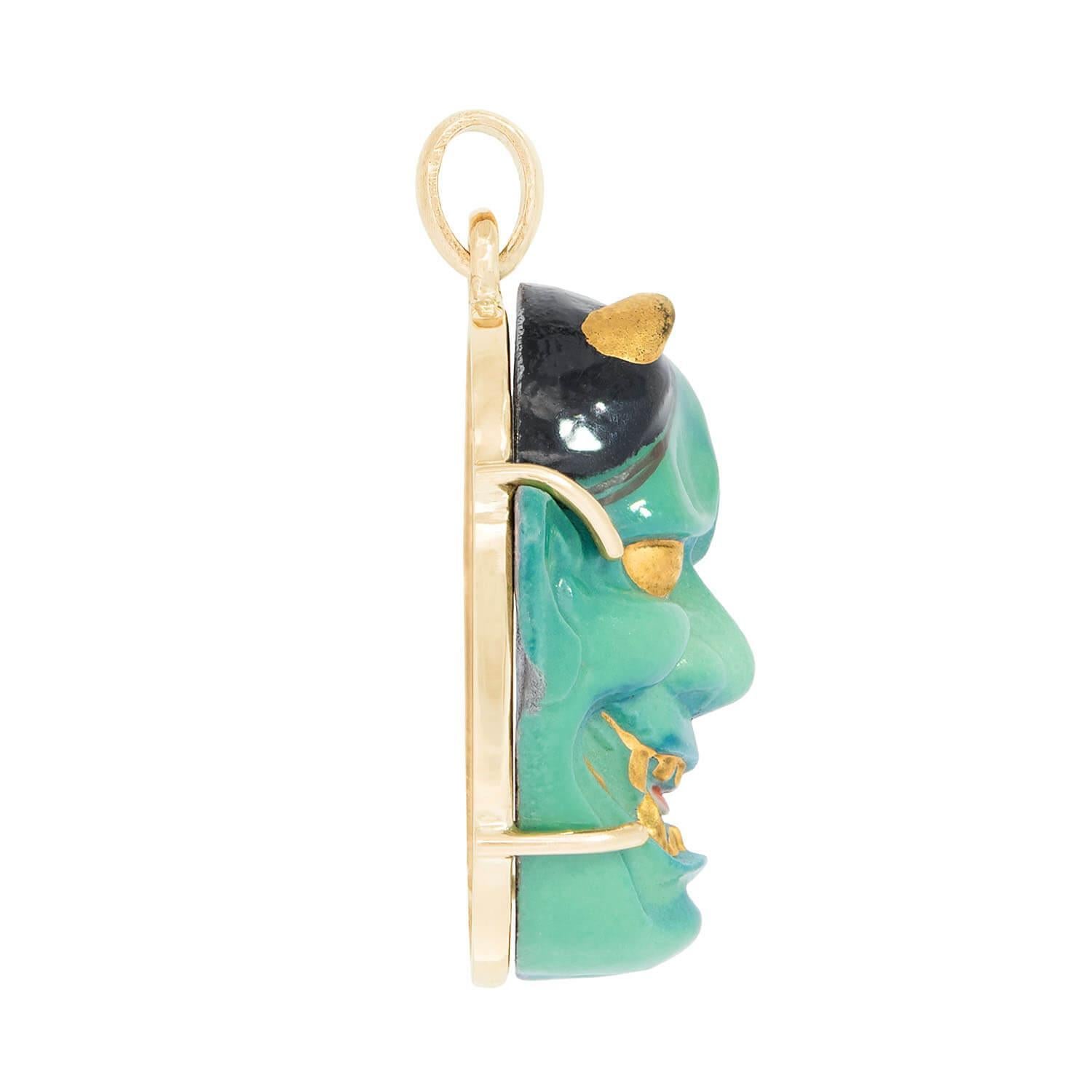 A fabulous devil pendant from the Vintage (ca1960s) era! Crafted in 14k yellow gold, the piece depicts the face of a hand-painted porcelain devil. The devil is held within a four-prong setting, and features greenish-blue skin, black hair, and gold