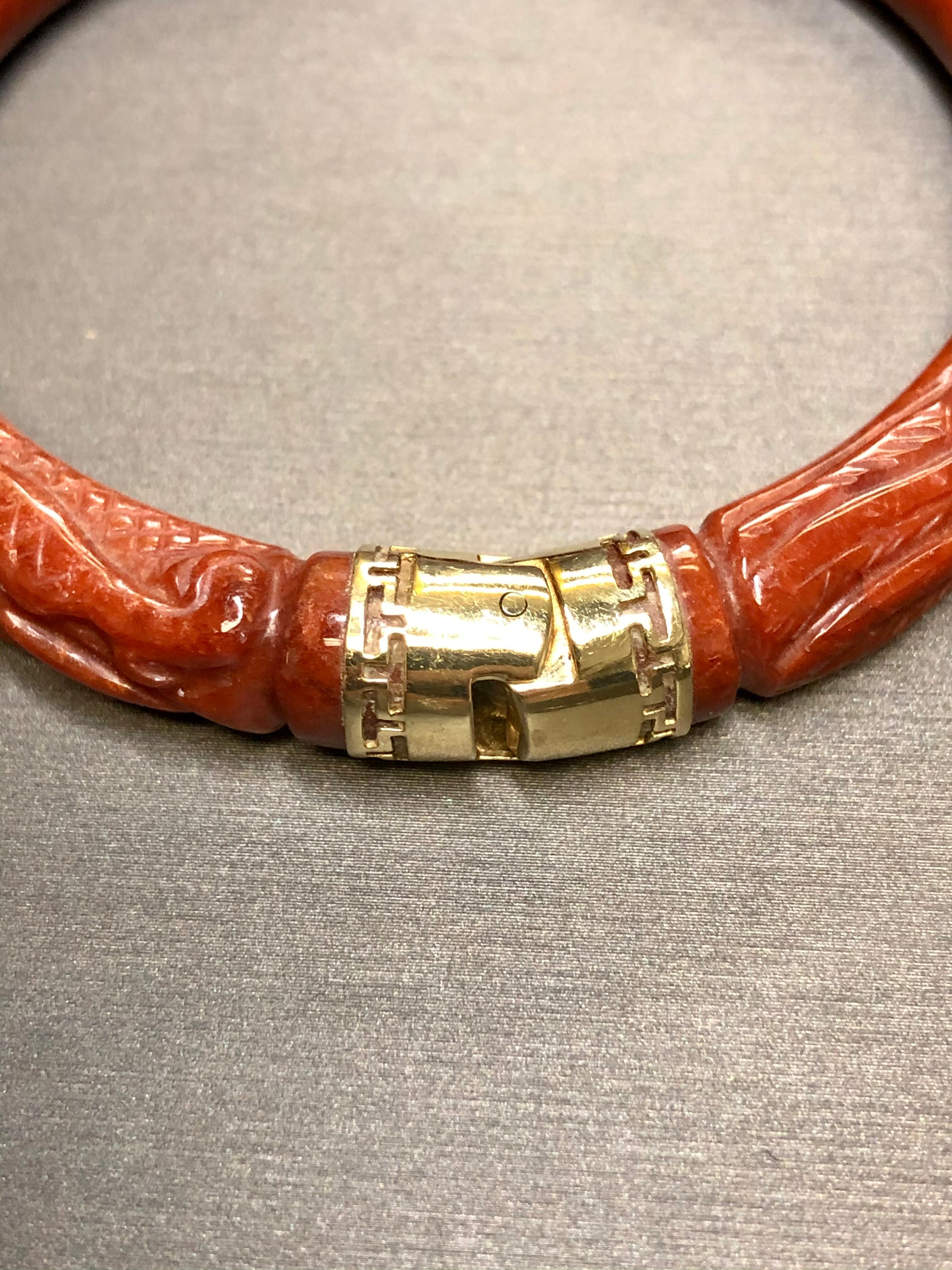 A beautiful and striking bangle bracelet  done in 100% natural red jade carved into a stylized dragon with its hinged portion in 14K.  

Dimensions/Weight:
Bracelet has an interior length of 7.25” and measures 9mm or .28” wide. Weighs 43.2g.