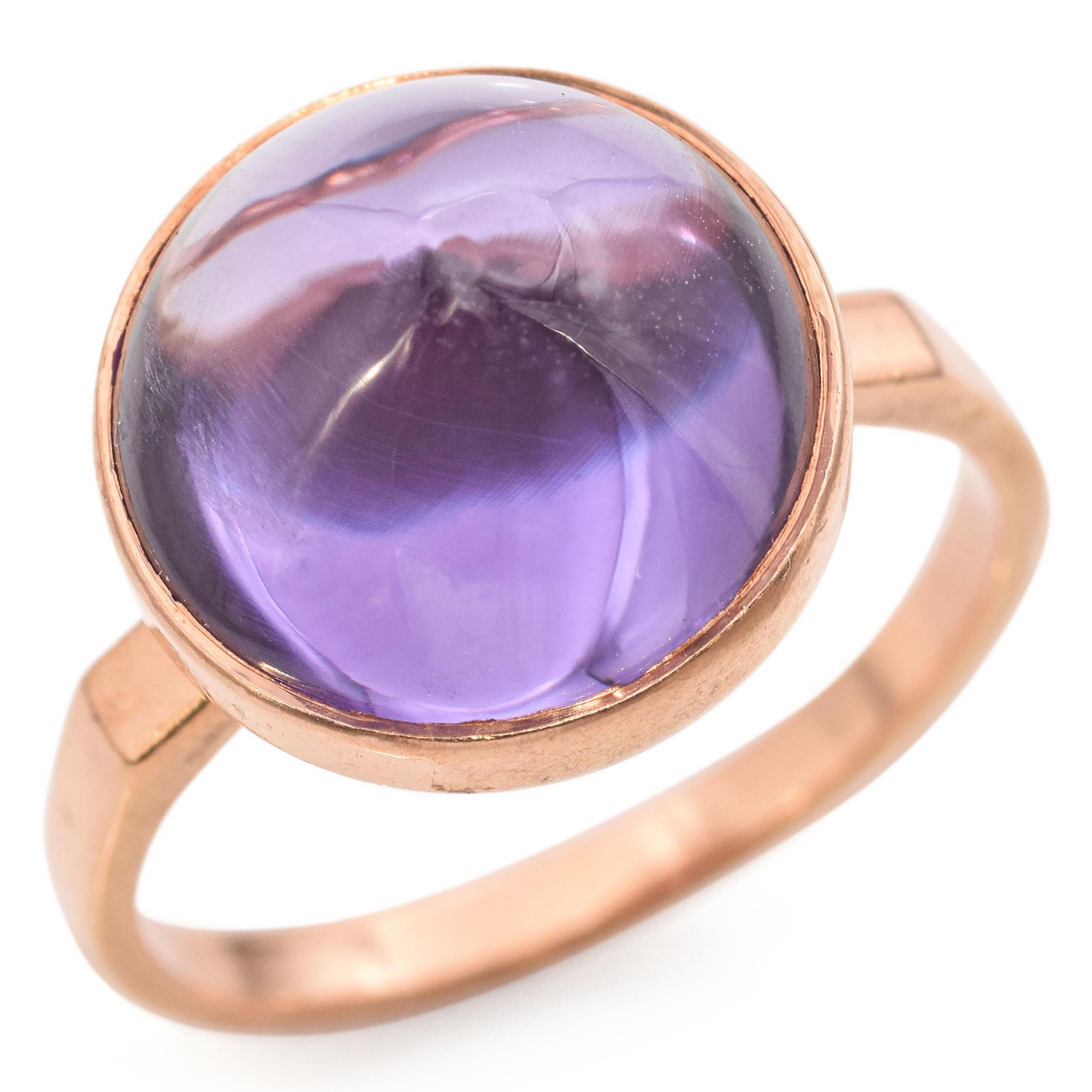 A Striking Ring set with a Purple Sapphire Cabochon Encased in a Warm Rose Gold Setting.

Weight: 4.7 Grams
Stone: 10.37 Ct. Purple Sapphire (12.25 x 12.25 x 6.4 mm)
Measurements: 13 x 19.6 x 9 mm
Ring Size: 7
Hallmark: M (hammer and sickle in