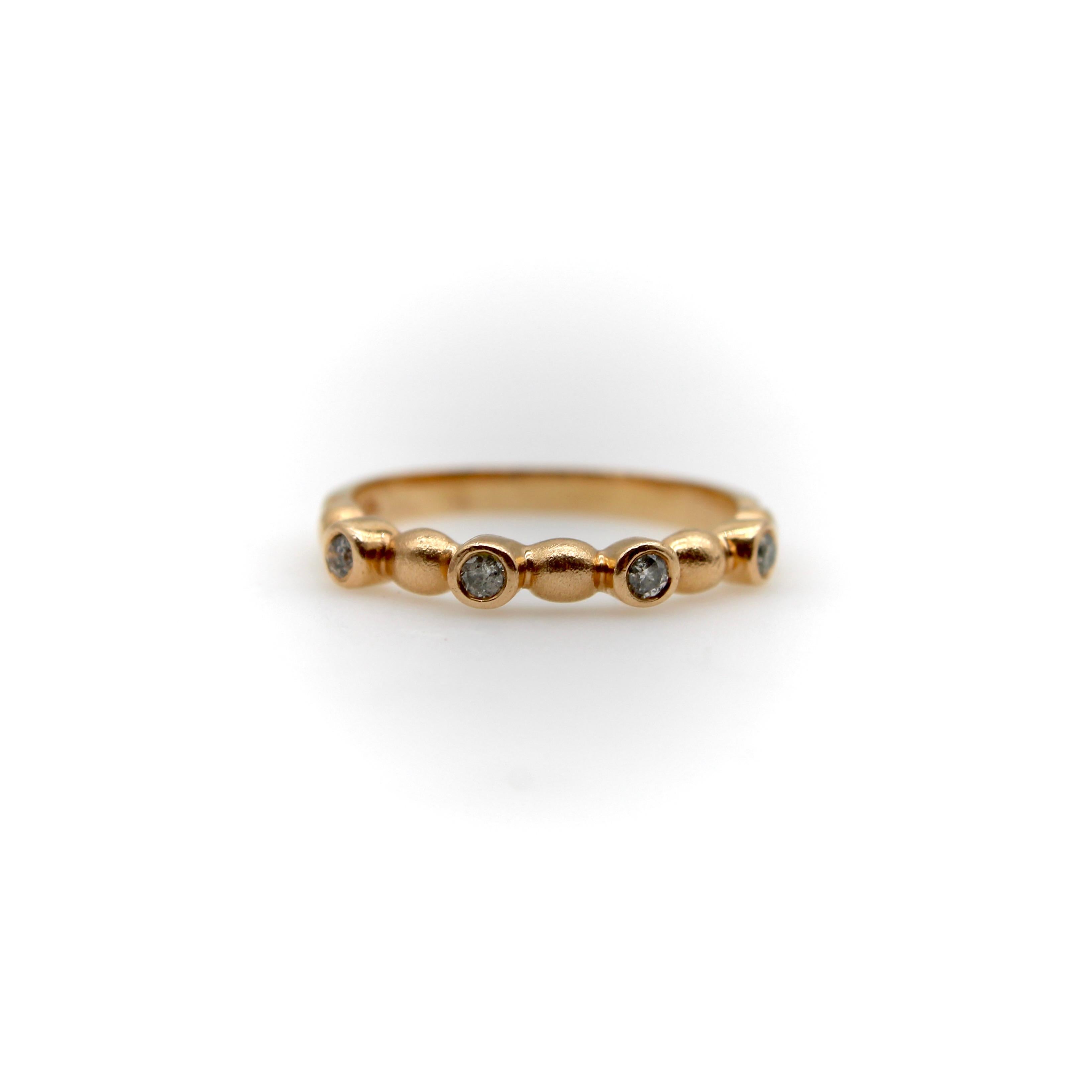 This vintage 14k rose gold ring is a great stacking ring, with a bubble pattern that alternates between round diamonds and bubble shapes. There are four round diamonds all bezel set, connected by five circular shapes. The ring is playful and