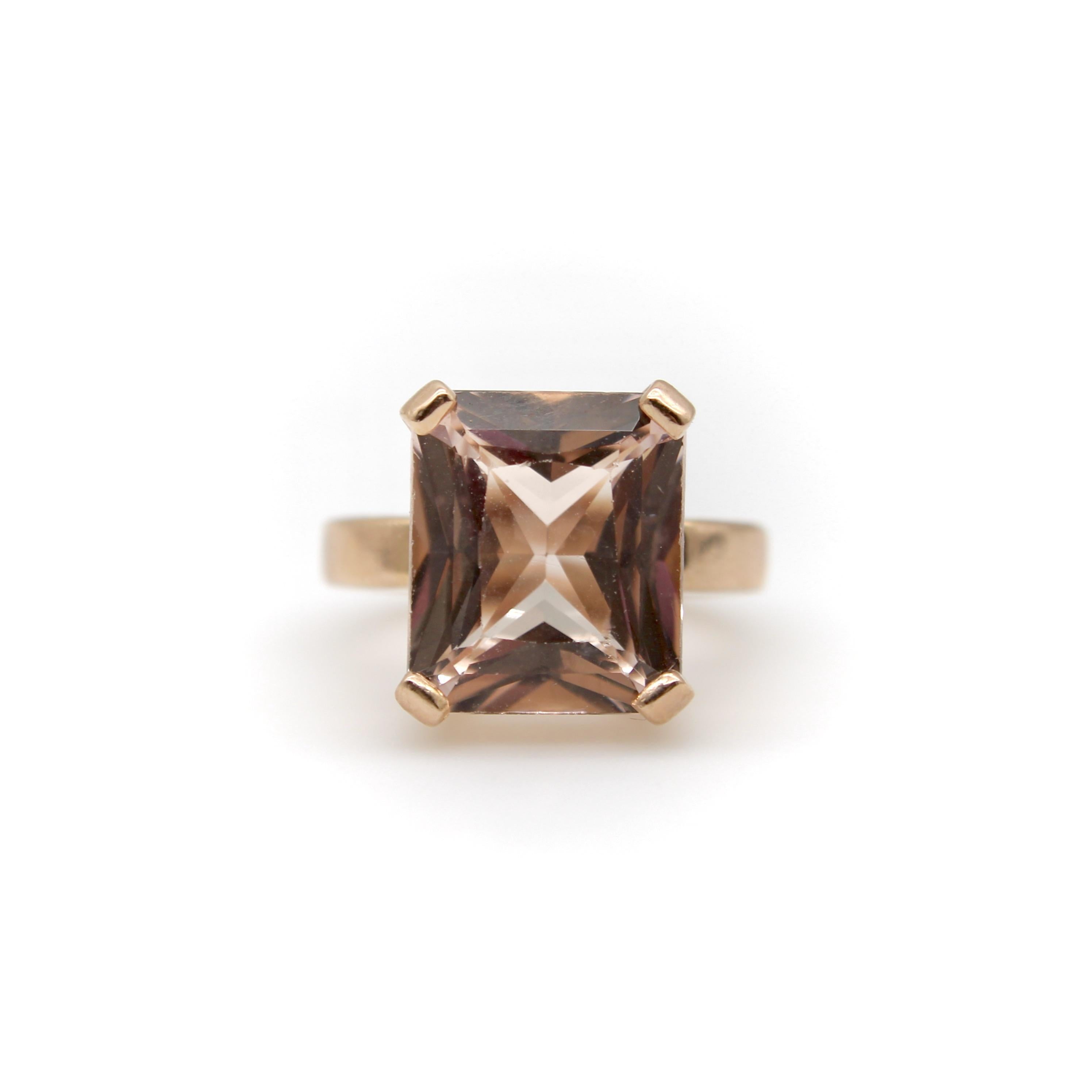 The golden hues of this 14k rose gold ring make a perfect complement to the peachy tones of the Morganite stone set within it. The ring has a very simple setting that highlights the emerald cut shape of the stone. The stone has a fancy cut—a deeper