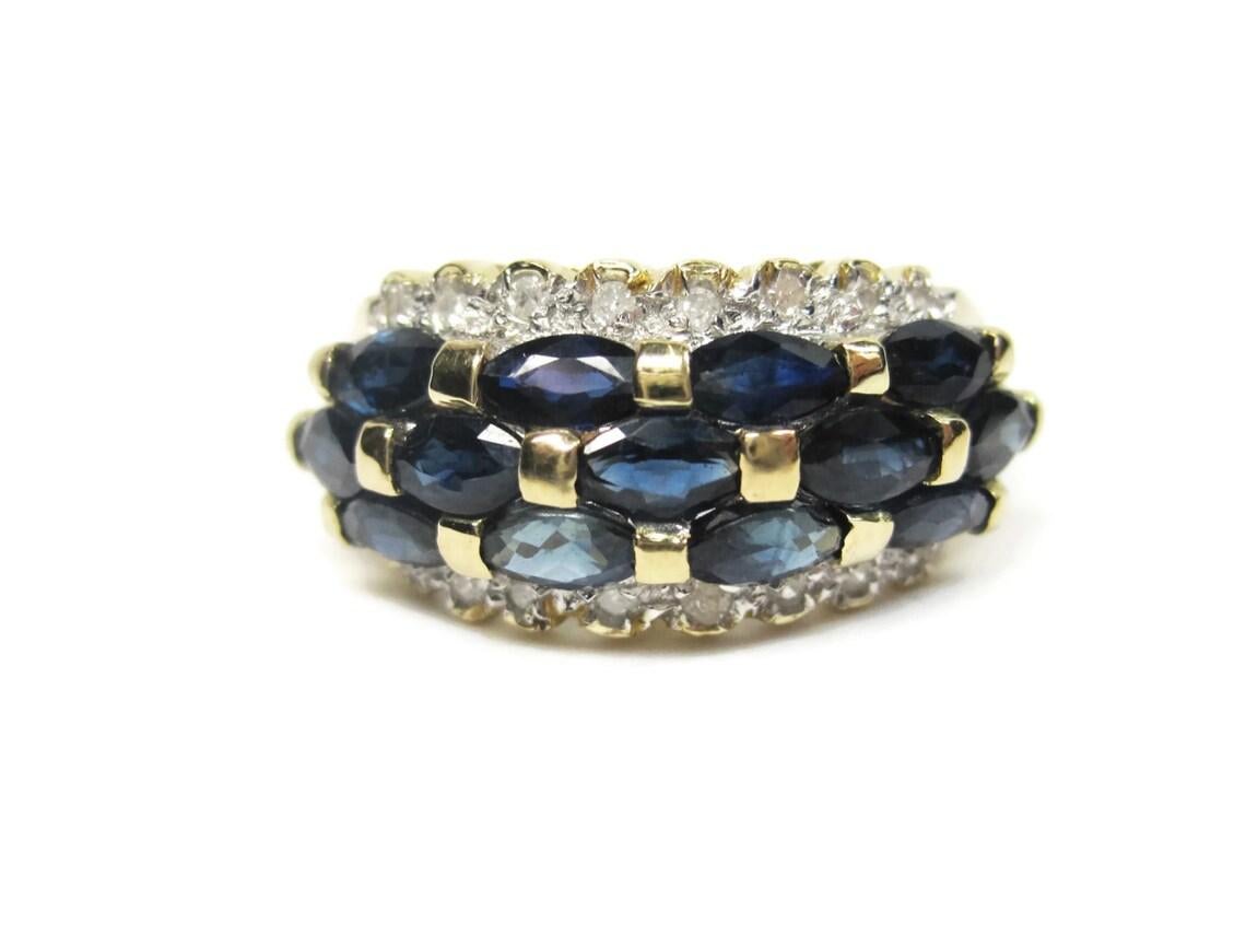 This beautiful vintage sapphire and diamond ring is solid 14k gold.

It features 3.25 ctw in marquise cut sapphires and .08 ctw in round cut diamond accents.
The face of this ring measures 3/8ths of an inch north to south.
It is a size 7.

Marks: