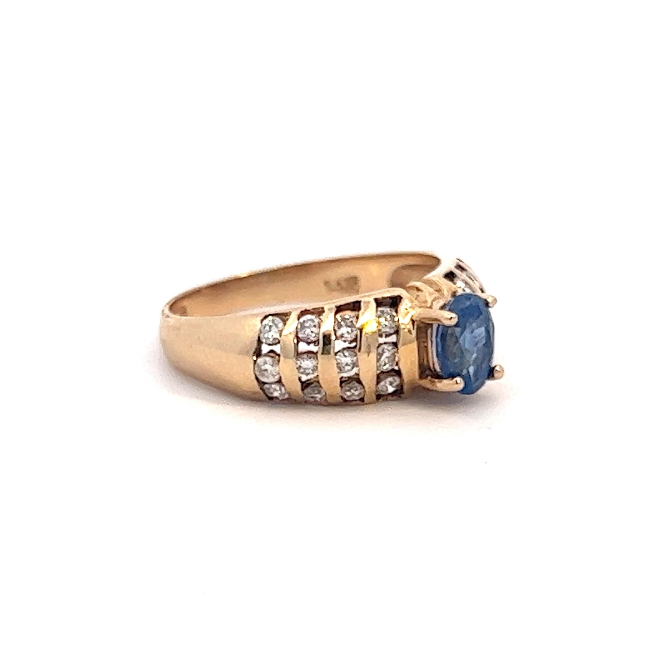 A vintage 14k yellow gold ring presenting an incredible sapphire among several rows of diamonds. The sapphire weighs approximately 1.17 carats and together, the diamonds weigh approximately .38 ctw (all stones measured in setting). The ring is a