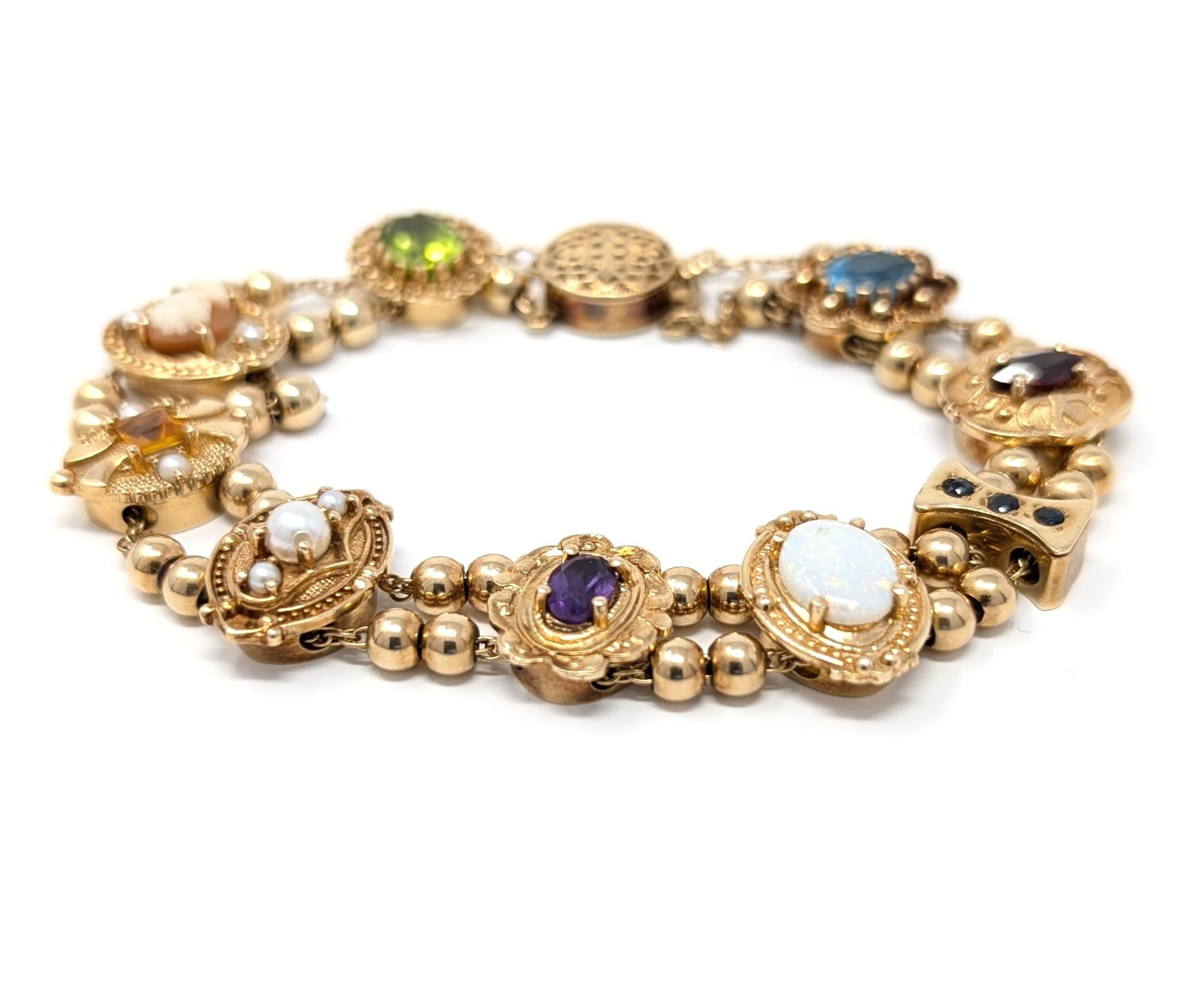 Elegant vintage slide bracelet featuring multi gemstone charms, set in 14k solid yellow gold. Adorned with pearls, carved shell cameo, amethyst, citrine, sapphires, and more. Signed RGVS 14K on the back of most slides for designer Richard Glatter.