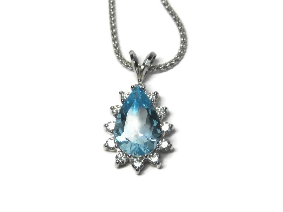 This stunning pendant is a custom made, early 90s to mid 80s piece.

It features a beautifully perfect 5 carat, pear cut blue topaz surrounded by a halo of 12 round cut .10 carat diamonds.
The total carat weight for the pendant is 6.20.

The
