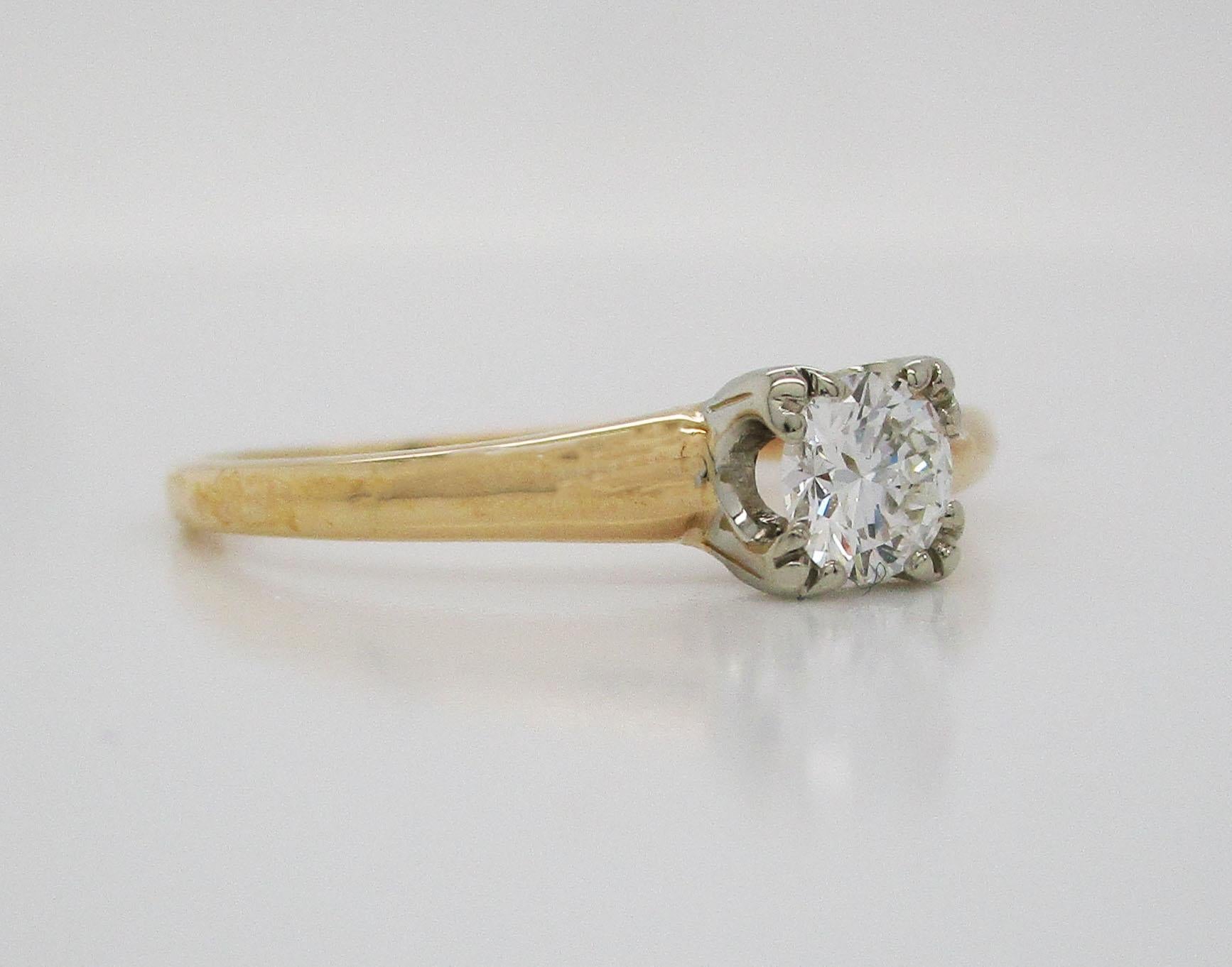 This adorable engagement ring is in 14k yellow gold and features a 14k white gold head, in which a stunning diamond is set! This is the perfect engagement ring for someone who appreciates the classic look of a traditional engagement ring, but is