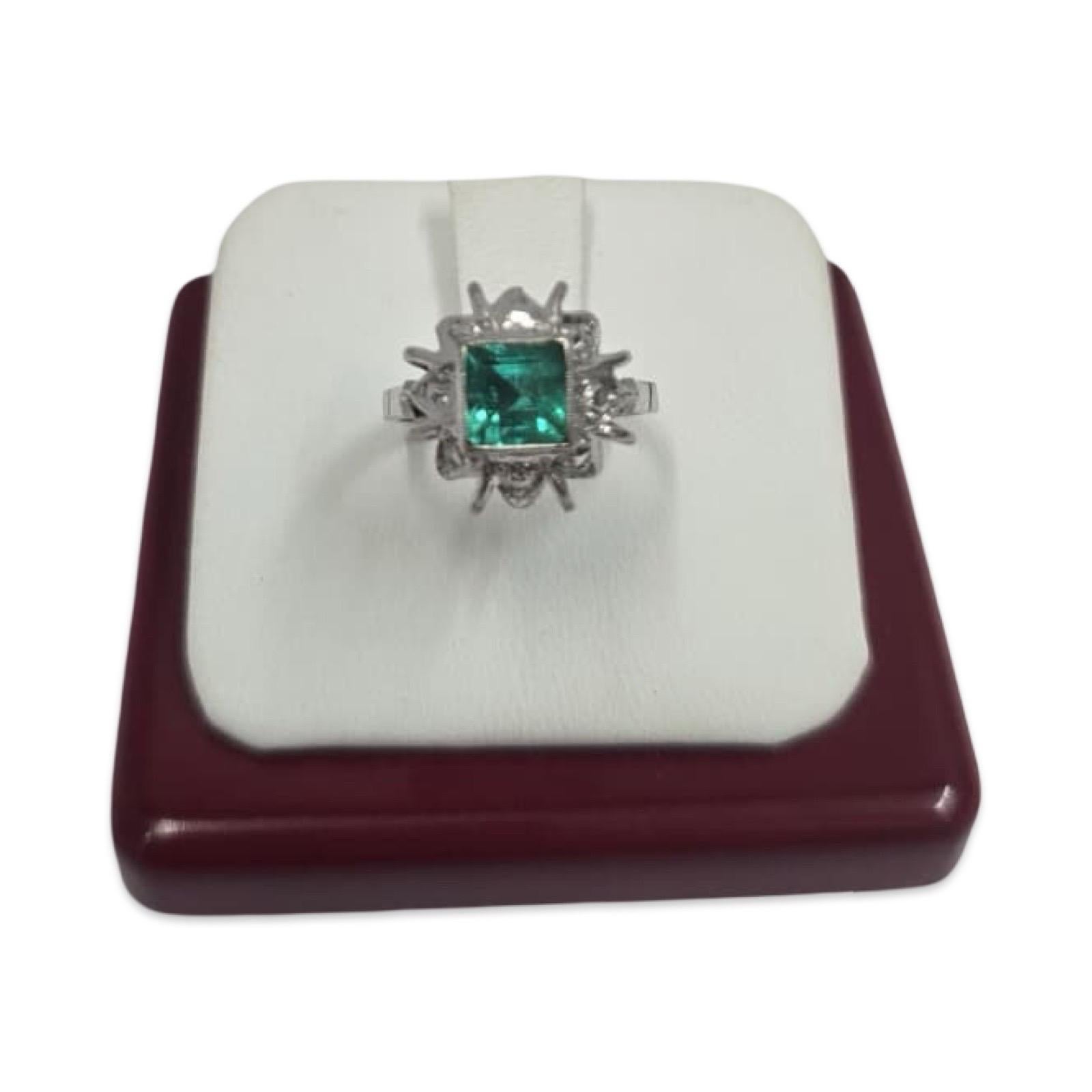 This exquisite vintage ring is crafted in solid 14K white gold and showcases a vibrant square-cut emerald weighing approximately 1.20 carats (6.5mm). The emerald is elegantly set in a sculptural filigree crown mounting, radiating with dimensional