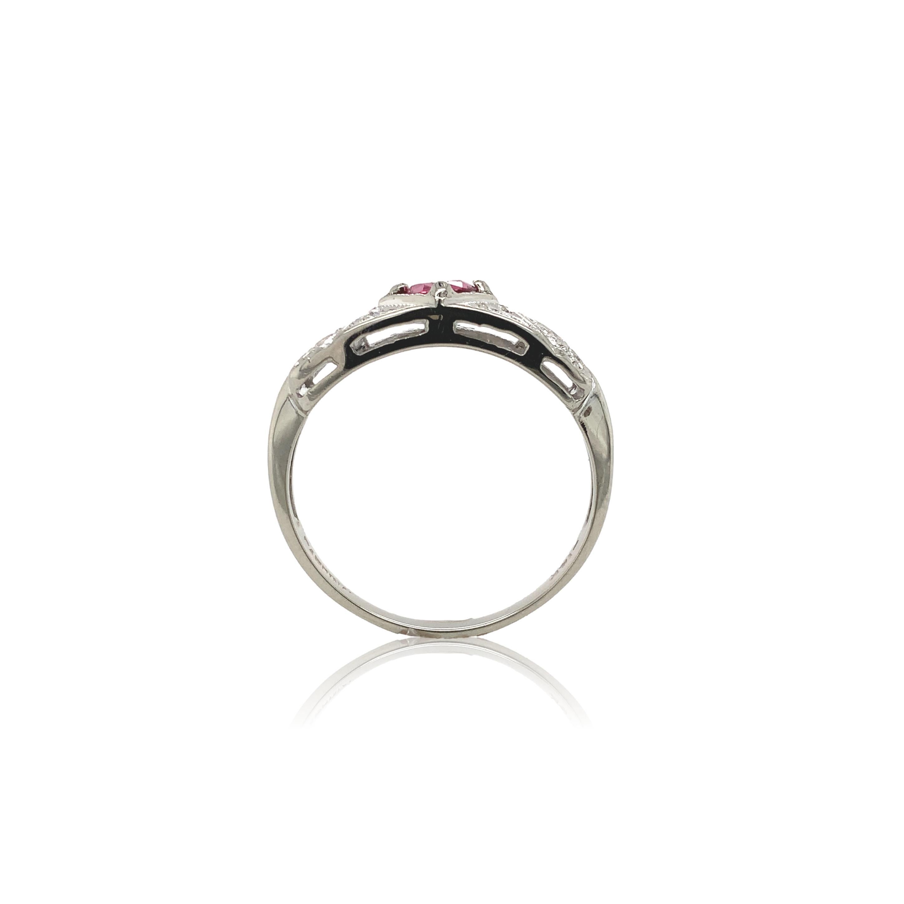 Vintage 14K white gold ruby and diamond ring. The ring features a genuine earth mined round pinkish-red ruby weighing .45cts. The ruby measures about 4.5mm. There are 9 small round brilliant cut diamond accents measuring about 1.5mm. There is chased
