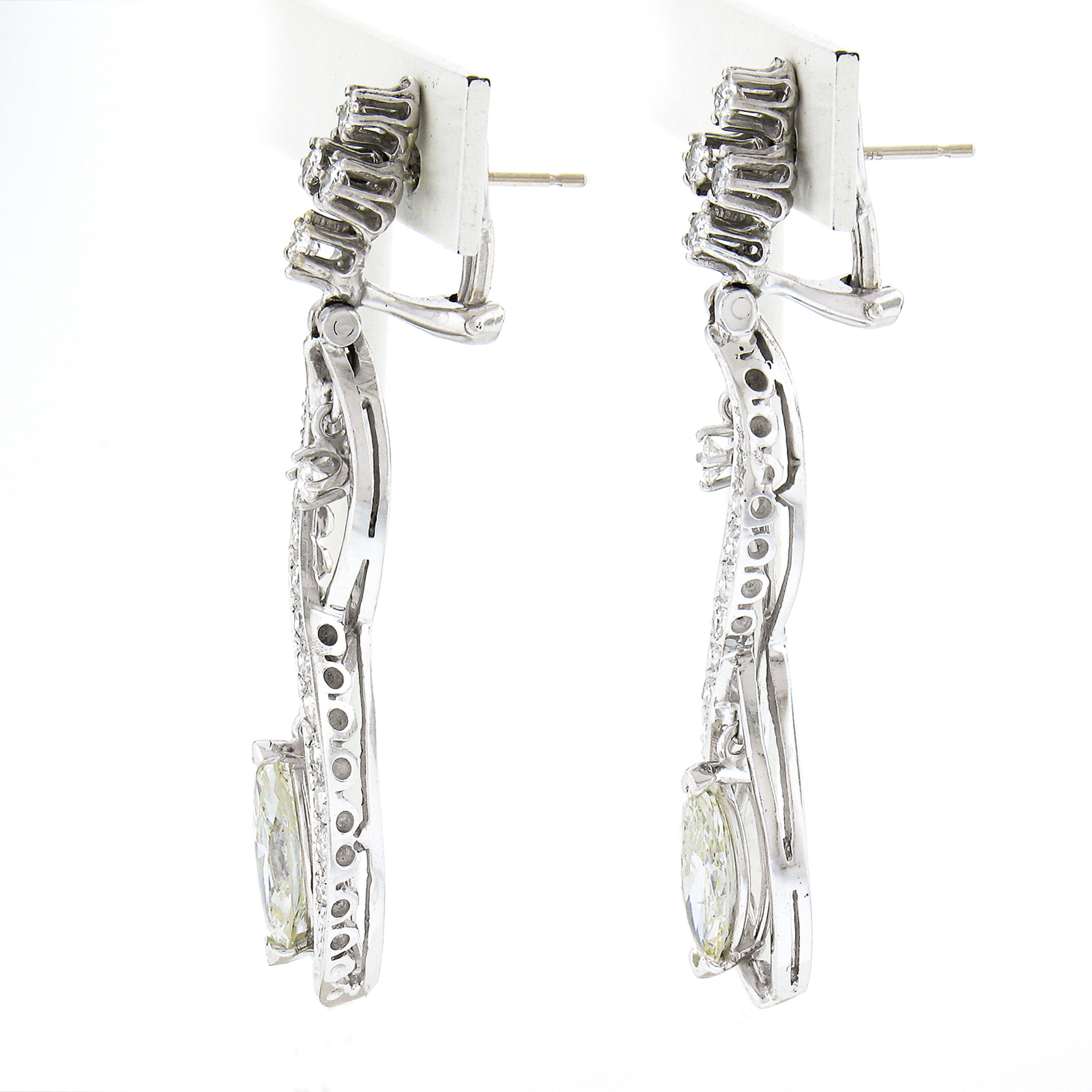 This breathtaking pair of vintage statement diamond dangle earrings is crafted in solid 14k white gold and features approximately 4 carats of very fine quality diamonds throughout. The long infinity design gently dangles from the top portion of the