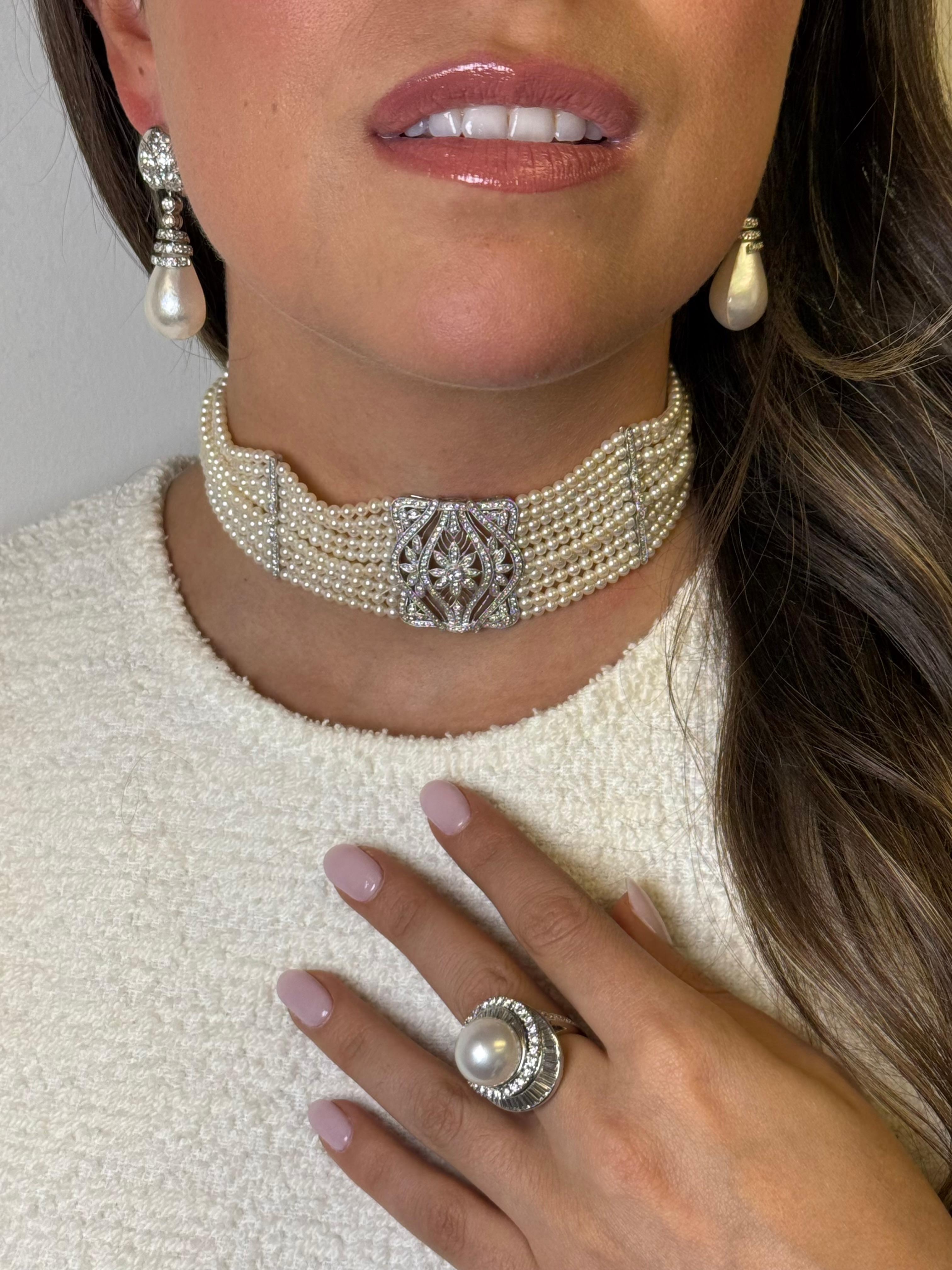 These exquisite vintage drop earrings are crafted in 14K white gold and feature lustrous baroque pearls suspended beneath an elegant cascade of sparkling diamonds. The tops are adorned with diamond-set floral motifs, while diamond-studded spiral