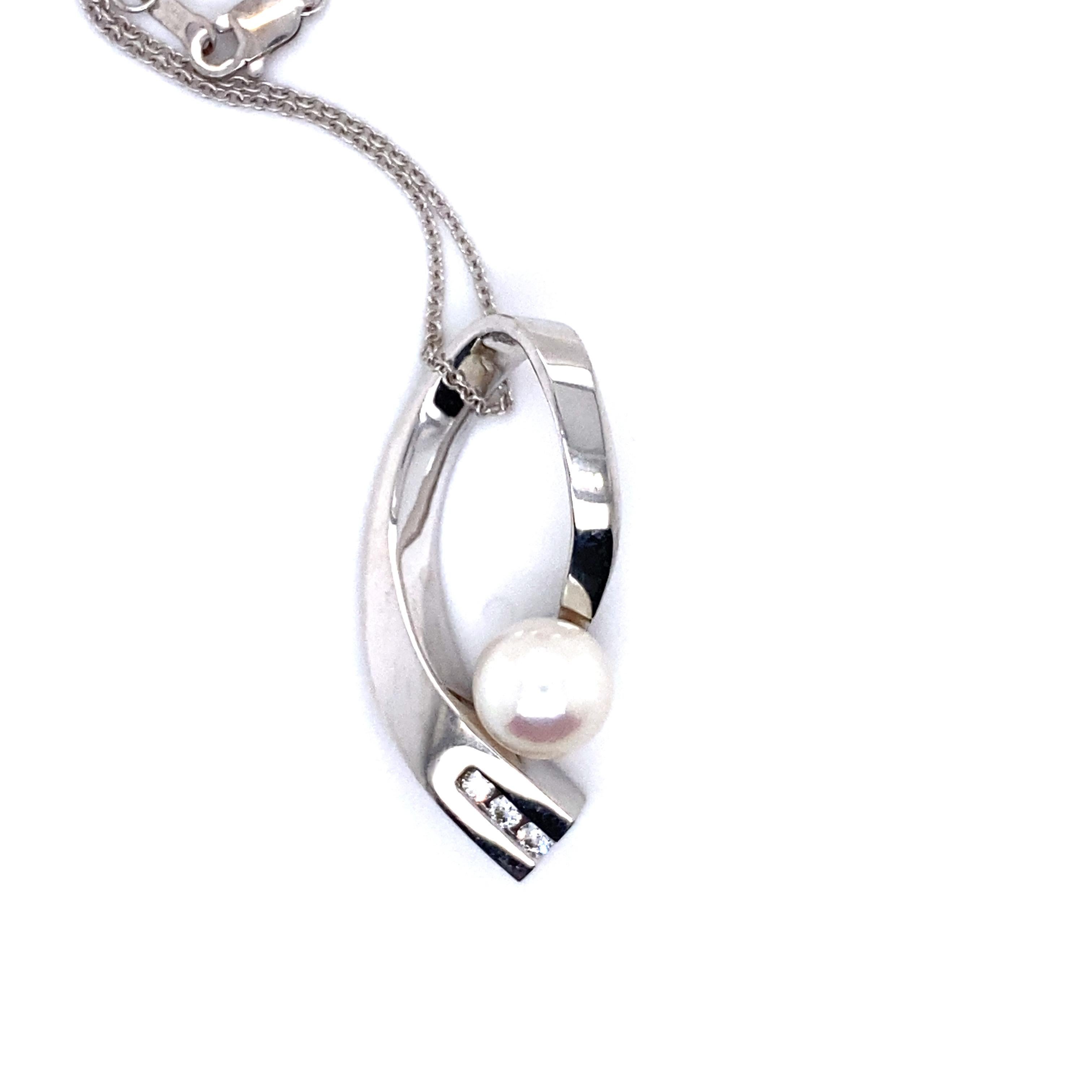 This Beautiful Vintage Diamond and Pearl Abstract Pendant with Chain is, well, just beautiful! Crafted in 14K White Gold, the design features a unique open shape, with a central cultured Pearl, accents with diamonds. In the center, the pendant holds