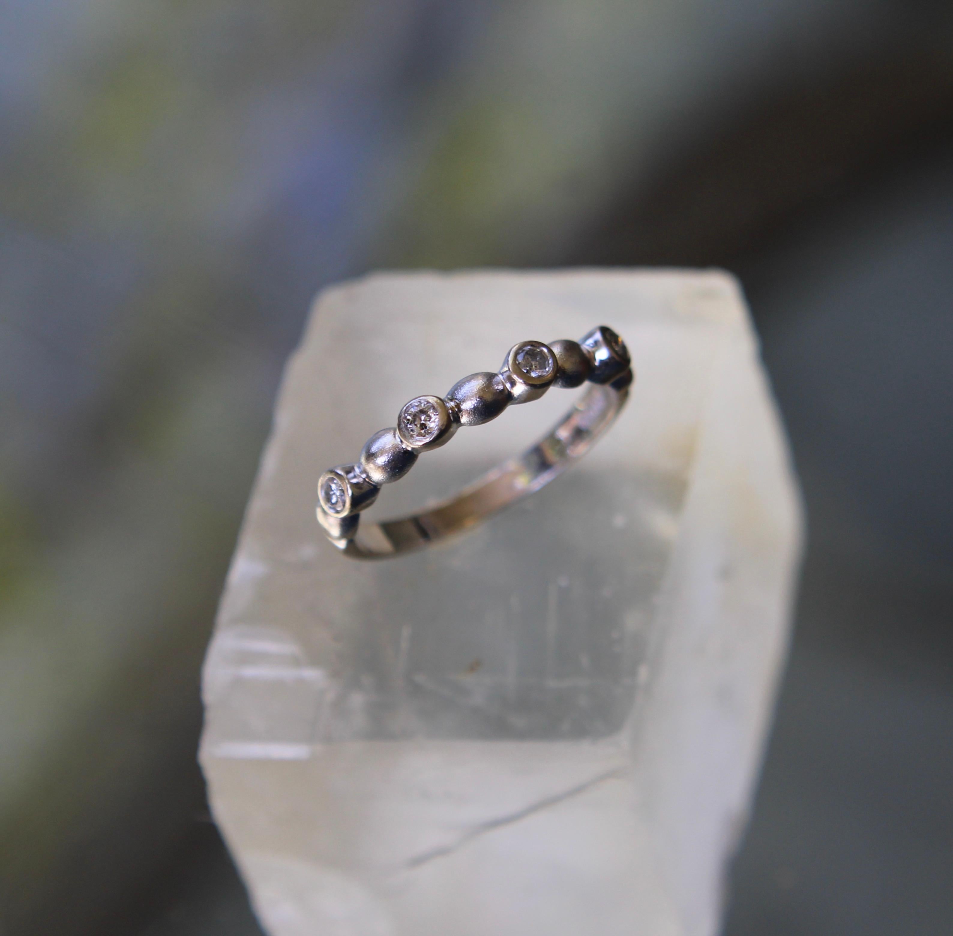 This vintage 14k white gold ring is a great stacking ring, with a bubble pattern that alternates between round diamonds and bubble shapes. There are four round diamonds all bezel set, connected by five circular shapes. The ring is playful and