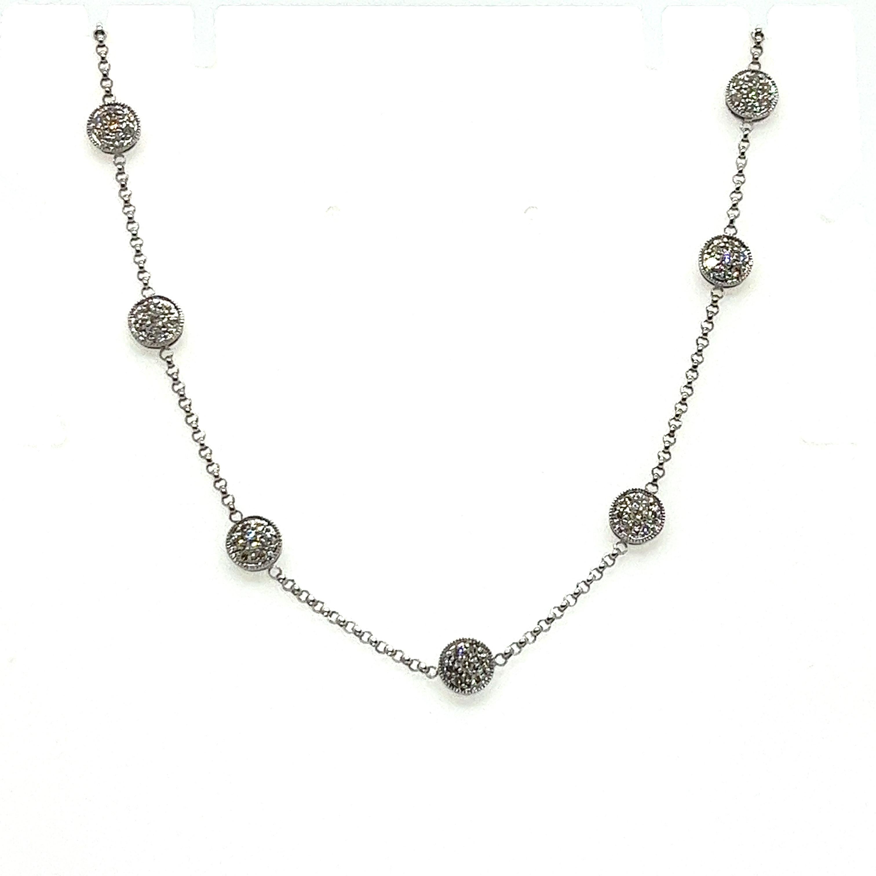 This elegant vintage necklace features a refined 14K white gold design, showcasing a series of 16 dazzling diamond cluster stations. Each cluster is composed of 7 round diamonds, with a total diamond weight of approximately 1.50 carats. The diamonds