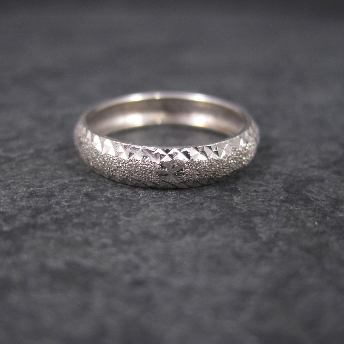 This beautiful band ring is 14k white gold.
It features a diamond cut starburst design.

Measurements: 4mm wide
Size: 5

Marks: 14K, SLC

Condition: Excellent