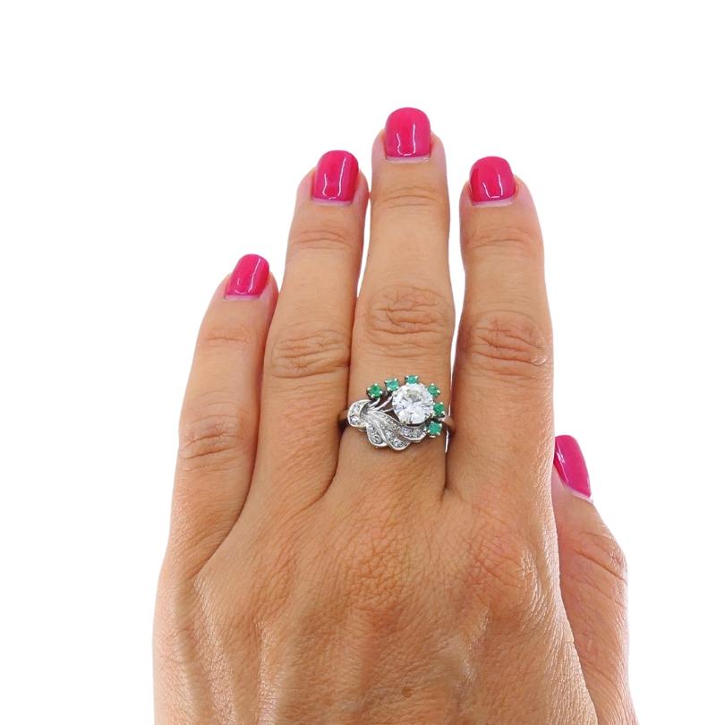 Un sorprendente anello da cocktail vintage realizzato in oro bianco 14 carati, che mette in risalto un diamante abbagliante al centro. I vivaci accenti di smeraldo verde creano un vivido contrasto, mentre un grazioso turbinio di diamanti incastonati
