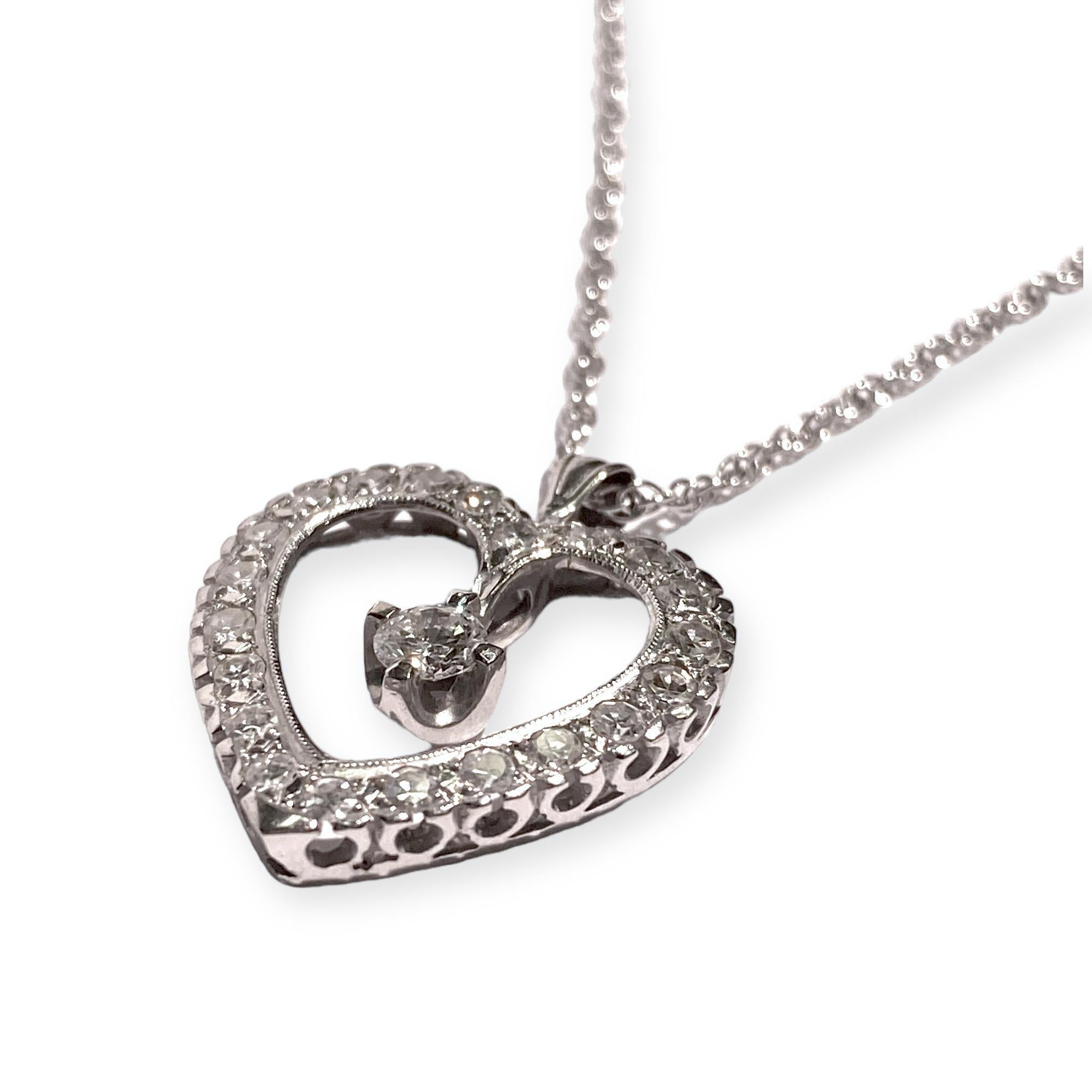 Crafted in 14K white gold, the pendant features a diamond set open heart design with a floating diamond solitaire in the center, supported by a twenty four inch twisted rope style chain with spring ring clasp.
1 round brilliant cut diamonds: