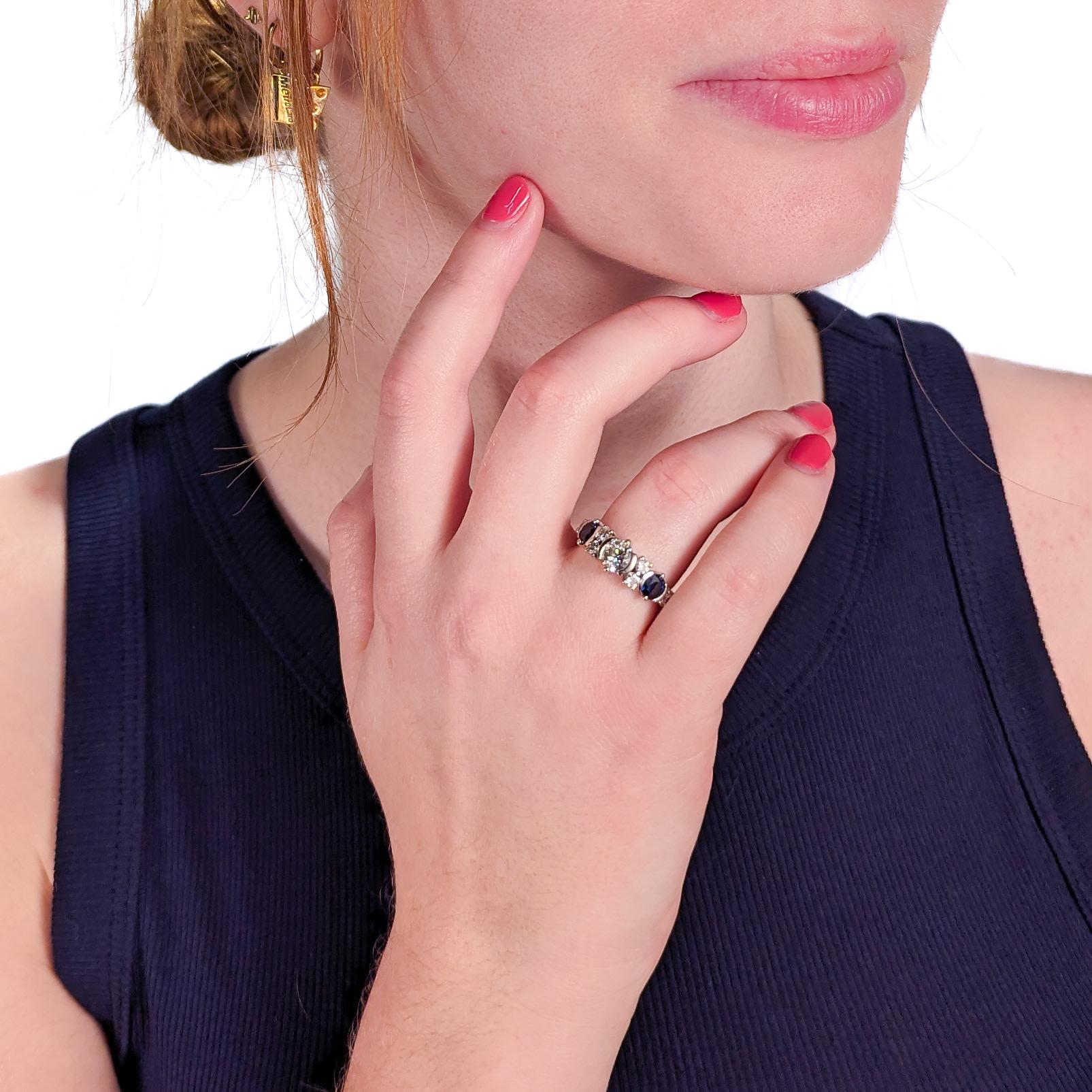 Un raffinato anello da cocktail in oro 14k, diamanti e zaffiri in stile Art Deco.

Con un peso totale di circa 2,50 carati di gemme e centrato da un bel diamante bianco rotondo taglio brillante, affiancato da 2 zaffiri blu taglio rotondo e da altri