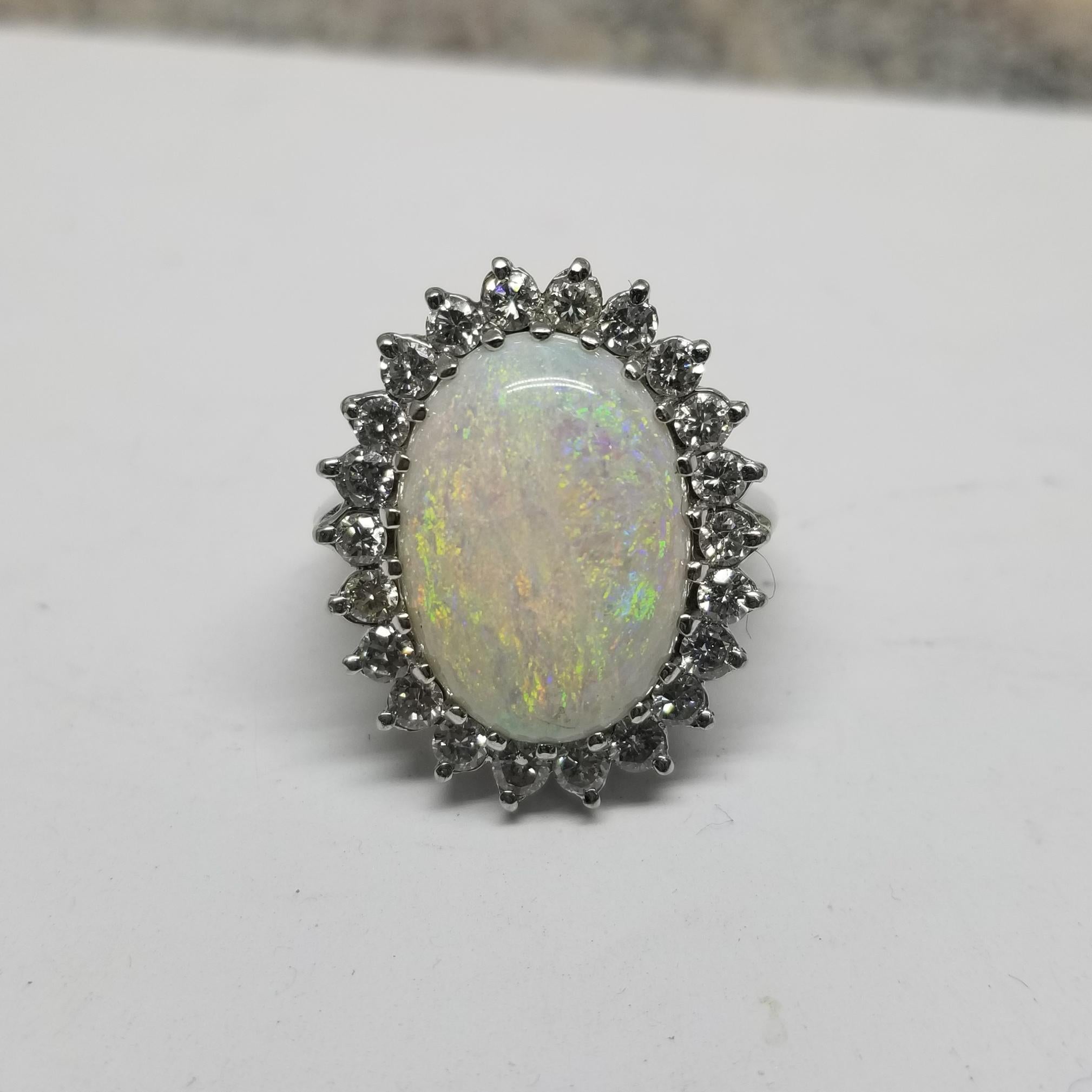 This beautiful Vintage 14k white gold fiery oval opal and diamond cocktail ring, containing 
Specifications:
    main stone: OVAL CUT OPAL STONE 18.20mm x 13.10mm
    weight: ESTIMATE 11.00CTS.
    diamonds: 22 PIECES ROUND CUT DIAMONDS
    carat