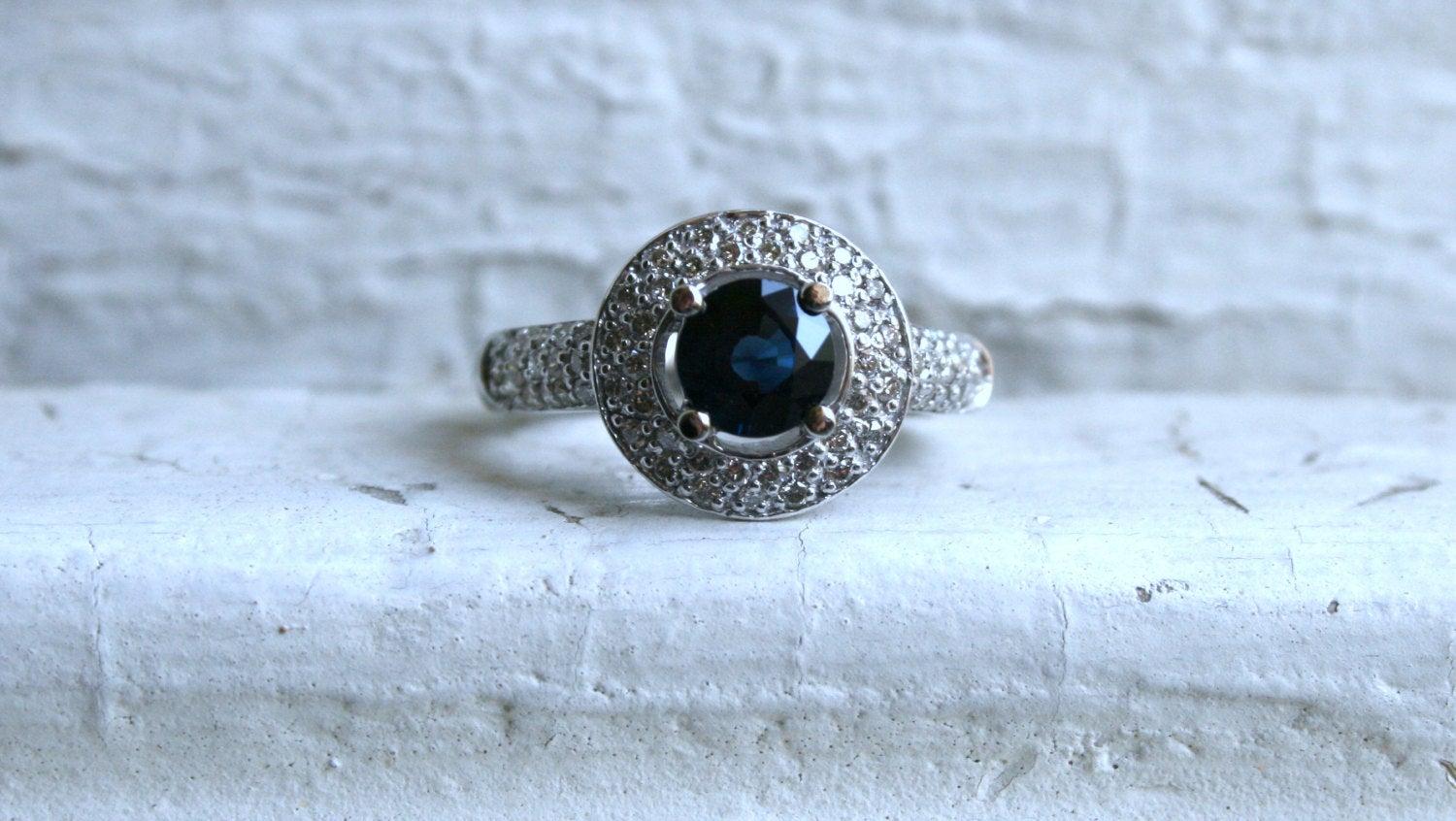 This Beautiful Vintage Pave Diamond and Sapphire Halo Ring is so stunning I'm temped to keep it for myself. Crafted in 14K White Gold, the design is a classic Halo, with a gorgeous central Sapphire, a double row of Pave Set Diamonds surrounding, and