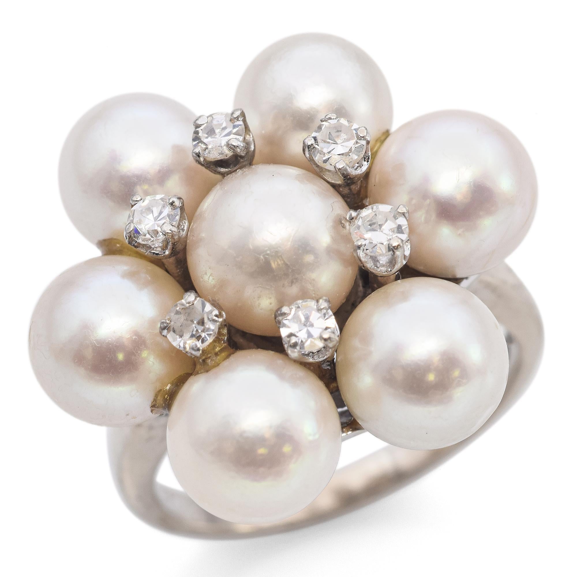 This captivating ring showcases a cluster of lustrous white pearls, each radiating a natural luster. Interspersed among the pearls are sparkling round-cut diamonds, totaling 0.24 carats, adding a touch of brilliance to the design. The setting is