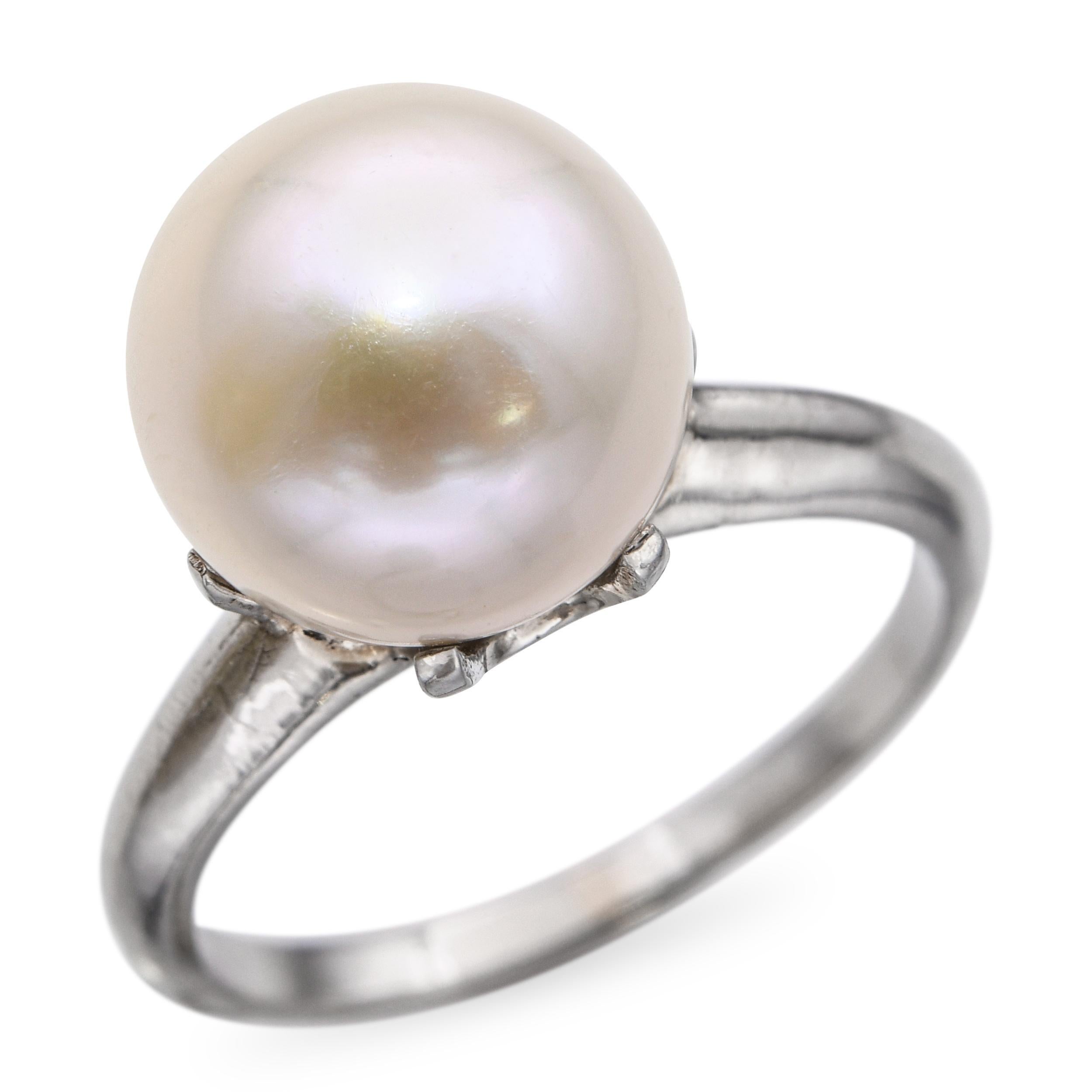 Dieser Vintage-Ring aus 14 Karat Weißgold zeigt eine einzelne schimmernde Perle in einer klassischen Solitärfassung. Die Perle ist elegant gefasst, um ihren natürlichen Glanz und ihre runde Form hervorzuheben, was ihr ein raffiniertes und zeitloses