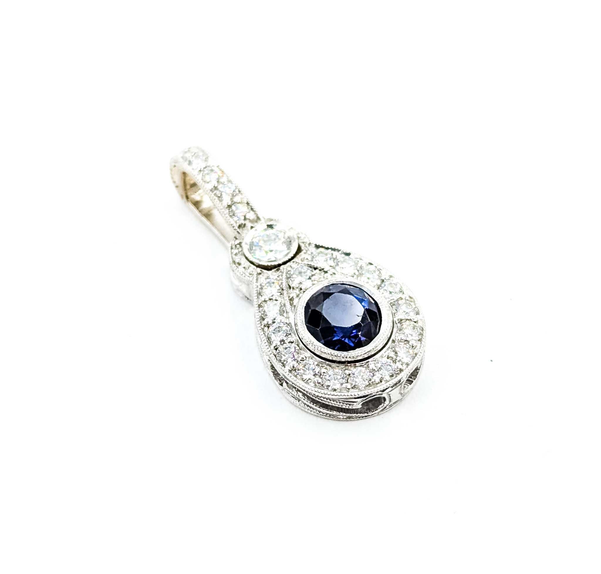 Questo elegante ciondolo a goccia è realizzato in oro bianco 14k e mette in mostra uno zaffiro blu dalle tonalità intense del peso di 0,75 carati. Lo zaffiro è circondato da una scintillante aureola di diamanti rotondi, con altri diamanti d'accento