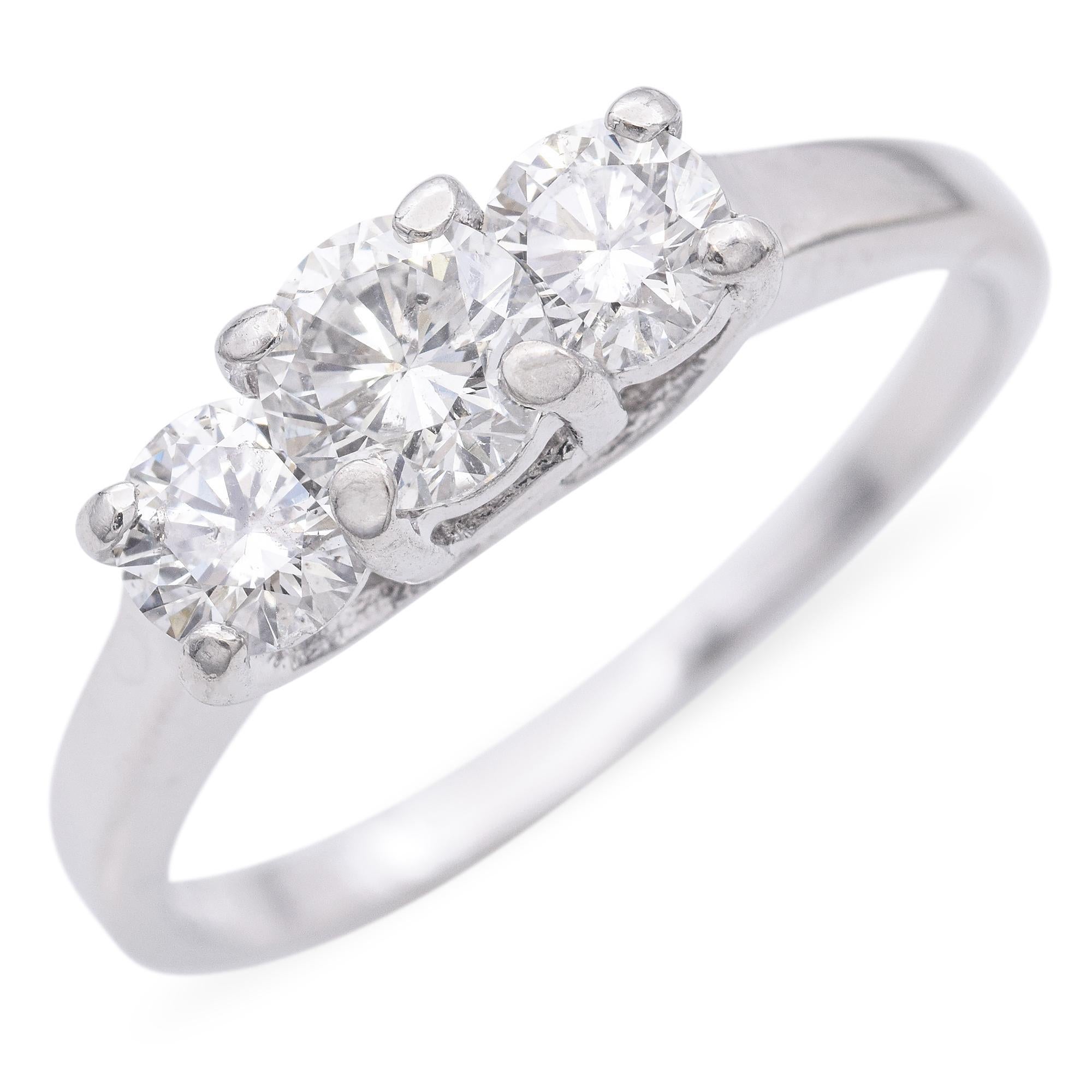 Realizzato in elegante metallo bianco, questo elegante anello presenta tre diamanti brillanti a taglio rotondo incastonati sul davanti. Le pietre sono tenute saldamente in posizione da incastonature a quattro punte in platino, che permettono loro di
