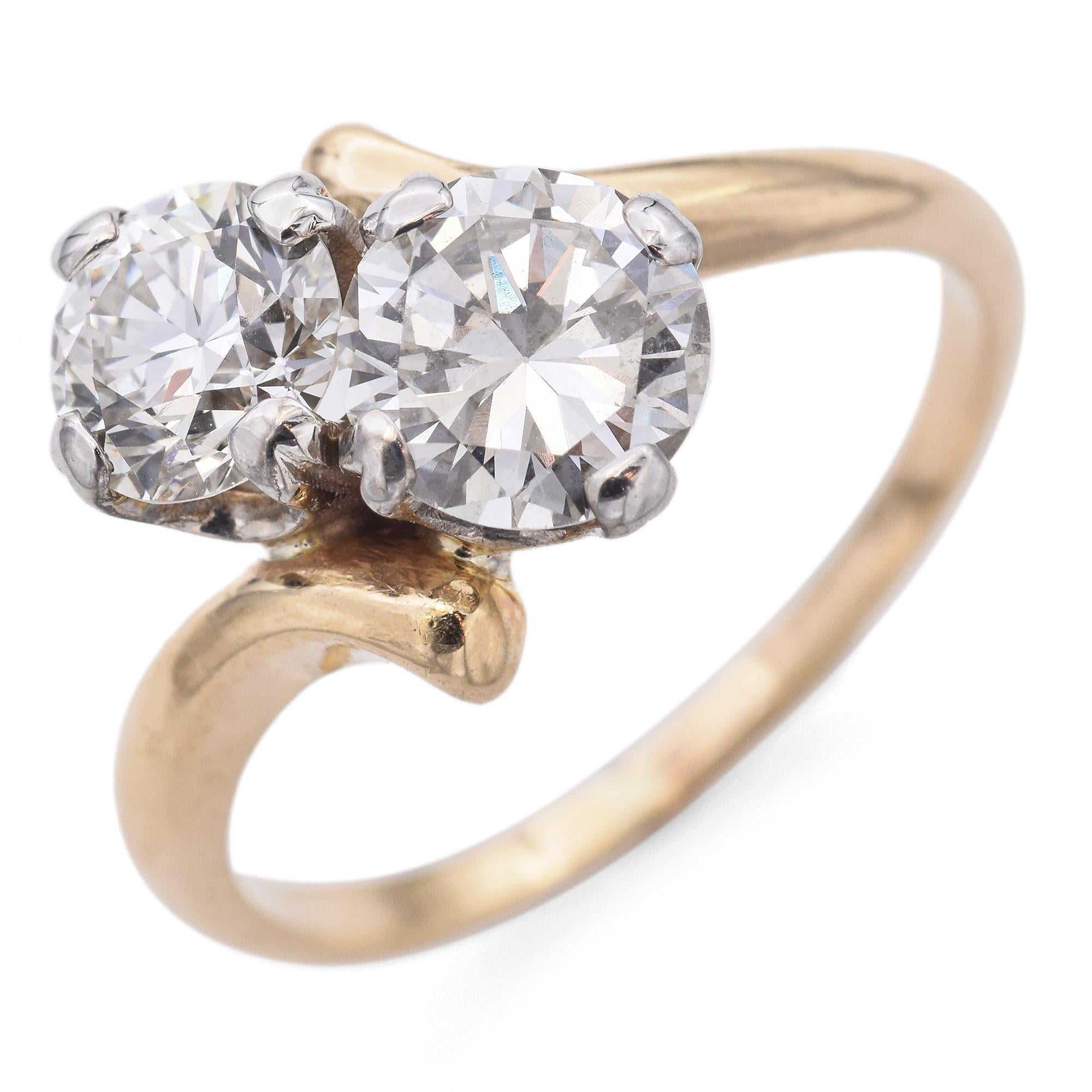 A stunning engagement ring. This exquisite piece features a 14k yellow gold band with a graceful, flowing design. The ring showcases two round-cut white diamonds, totaling 1.63 carats, set in a secure 14k white gold prong setting, enhancing their