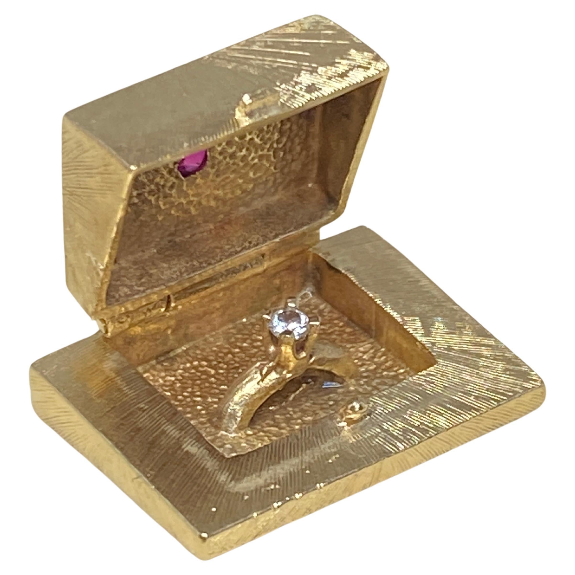 Charming vintage mid century box charm crafted in 14 karat yellow gold with florentine finish, adorned with a sparkling faceted ruby at the top.   The box top lifts from the hinge to reveal a sweet diamond solitaire ring.  This is a beautiful  charm