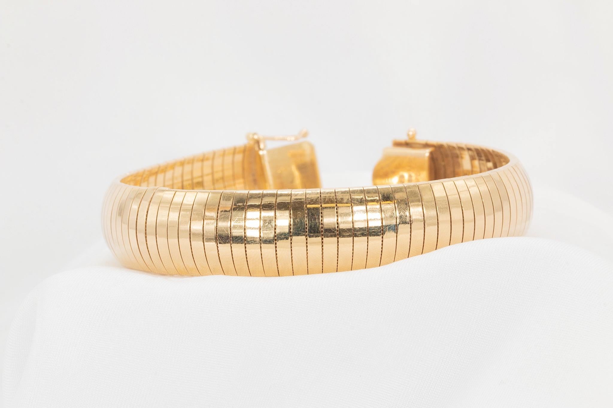 This stunning vintage 14k yellow gold omega flex bangle is a true statement piece. Weighing 43.5 grams, it measures 7.5 inches in length and 13.8mm in width, showcasing bold elegance and craftsmanship. As an authentic vintage item, it features light
