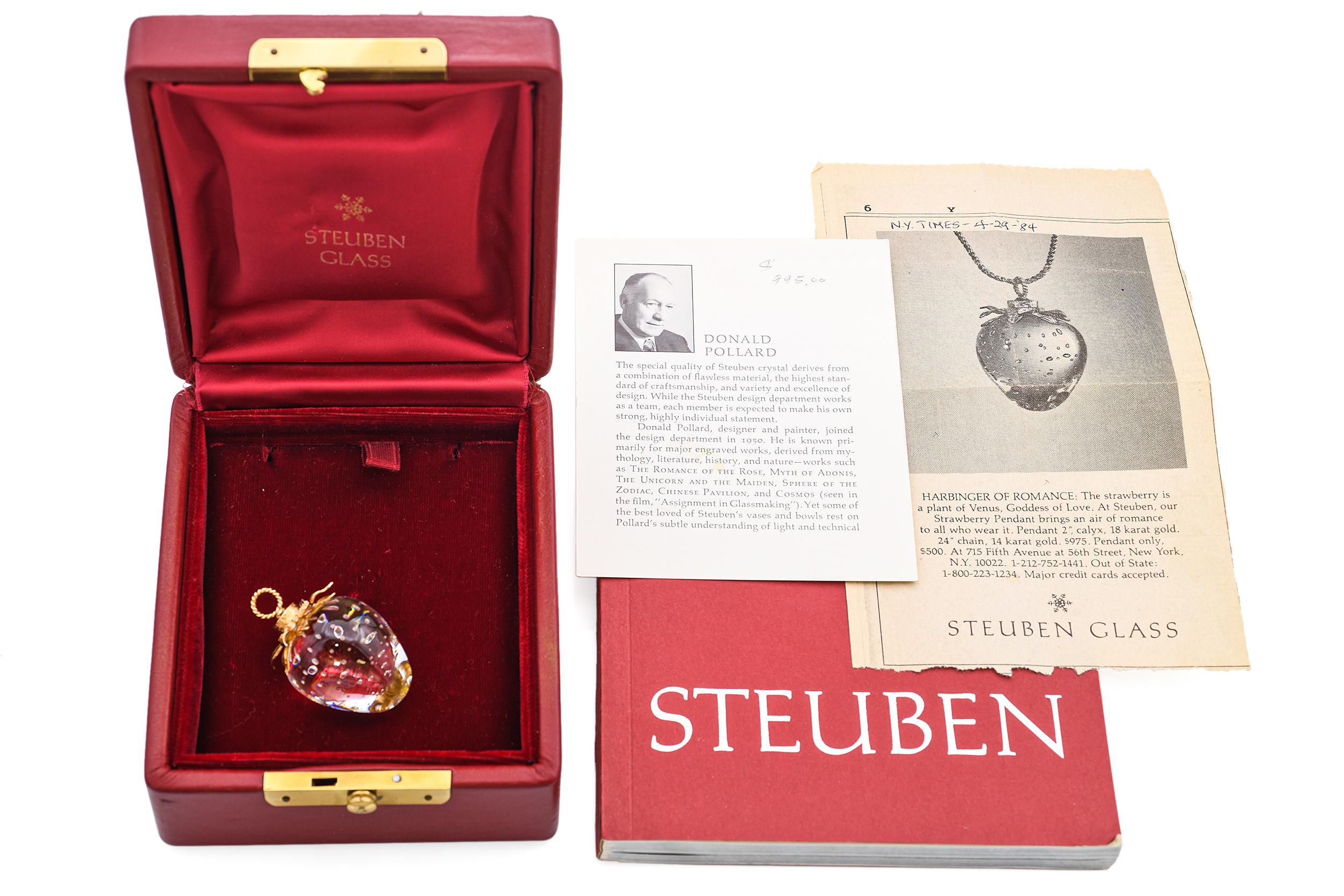 Questo affascinante ciondolo vintage presenta una fragola in cristallo Steuben finemente lavorata, sospesa a un cappuccio e a una coda in oro giallo 14k. Il cristallo chiaro e scolpito riflette la rinomata abilità artistica e l'attenzione ai