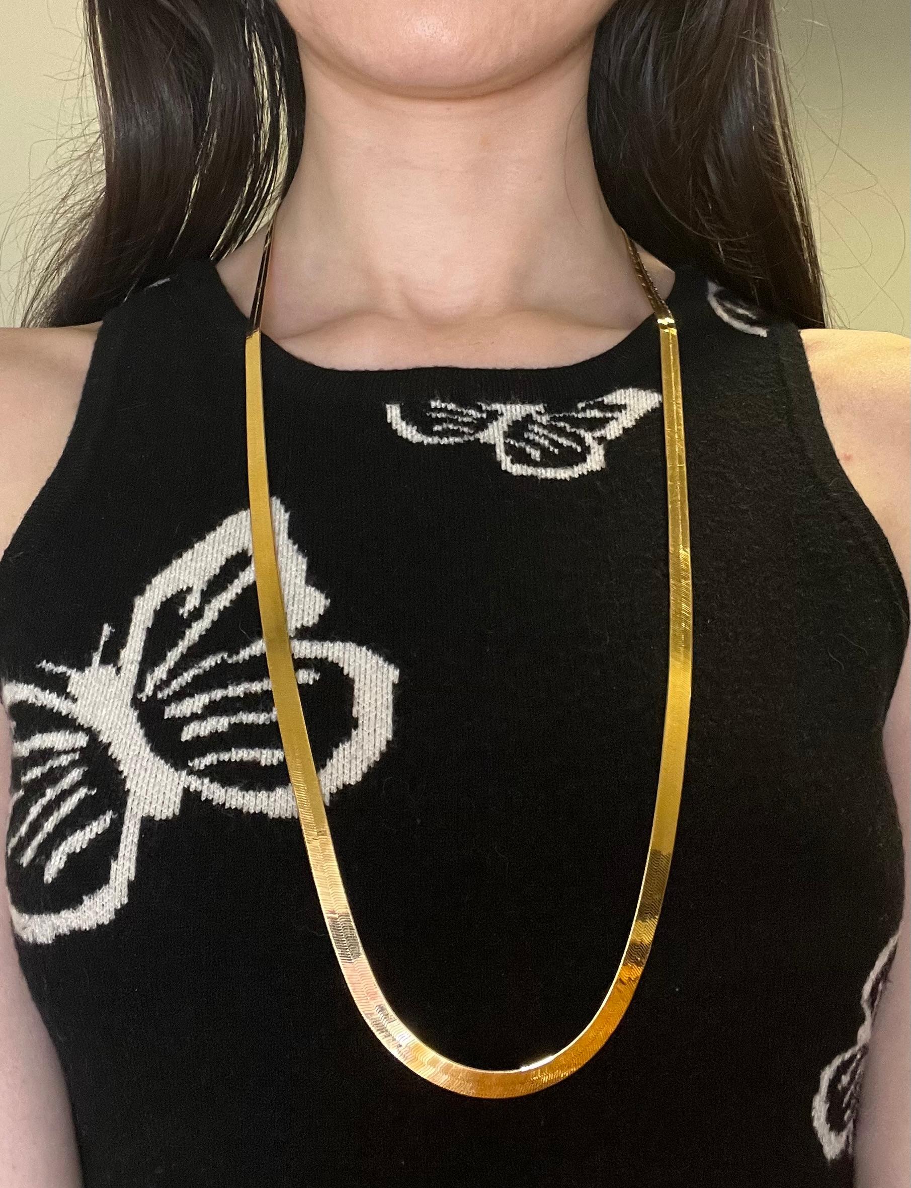 Elegant and timeless, this vintage 1990's 14k yellow gold herringbone necklace is a stunning piece of jewelry that combines classic style with substantial presence. 

At an impressive 30 inches in length, this necklace offers a dramatic look. The