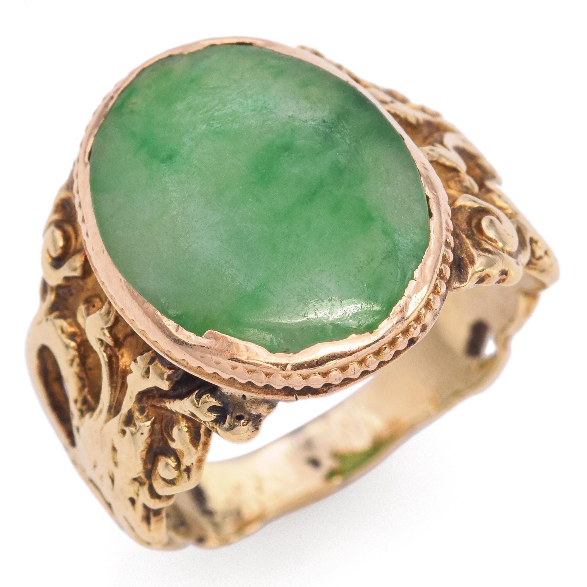 This striking ring showcases a captivating 3.7 carat green jade cabochon. The smooth, polished stone is set in an ornate 14k gold band, featuring elaborate dragon design that enhances its regal appearance. A unique piece for those who appreciate the