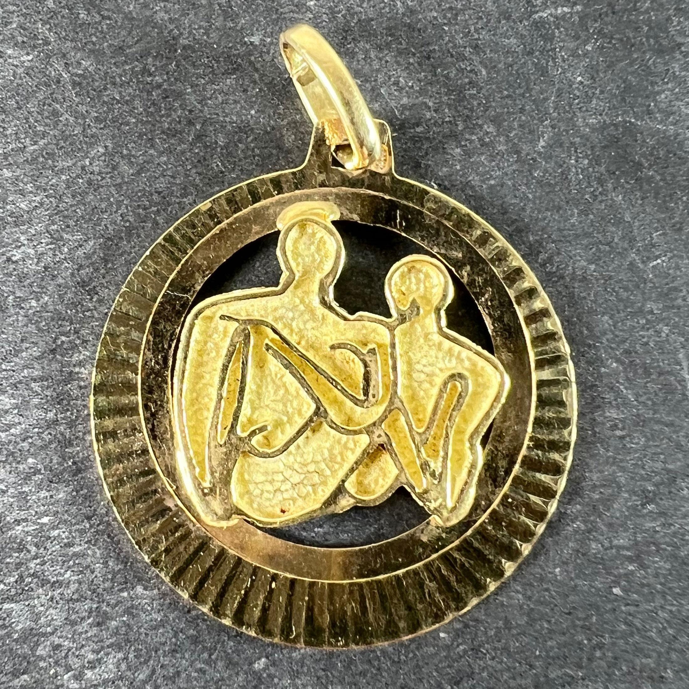 A vintage 14 karat (14K) yellow gold pendant medal depicting a couple of lovers in an embrace in the abstract art style of Henry Moore. Stamped 585 for 14 karat gold with an unknown maker's mark SG1+.

Dimensions: 2.4 x 2.2 x 0.17 cm (not including