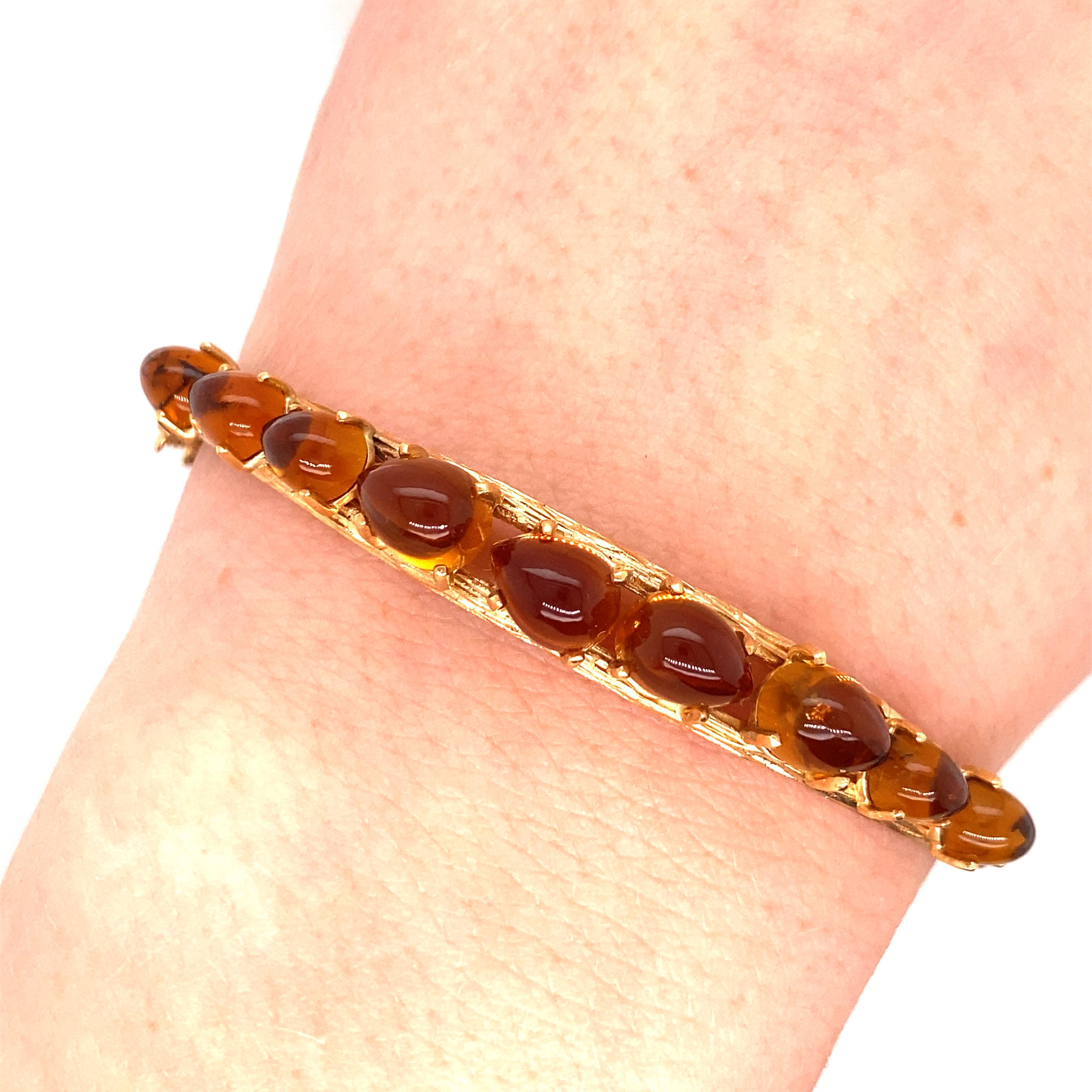 Vintage 14K Yellow Gold Amber Bangle Bracelet - The bangle has 9 cabochon pear shape Amber stones graduated in size and they are set in 4 prong heads. The gold bangle has a natural texture and is .25 inches wide with a slight taper. The inside