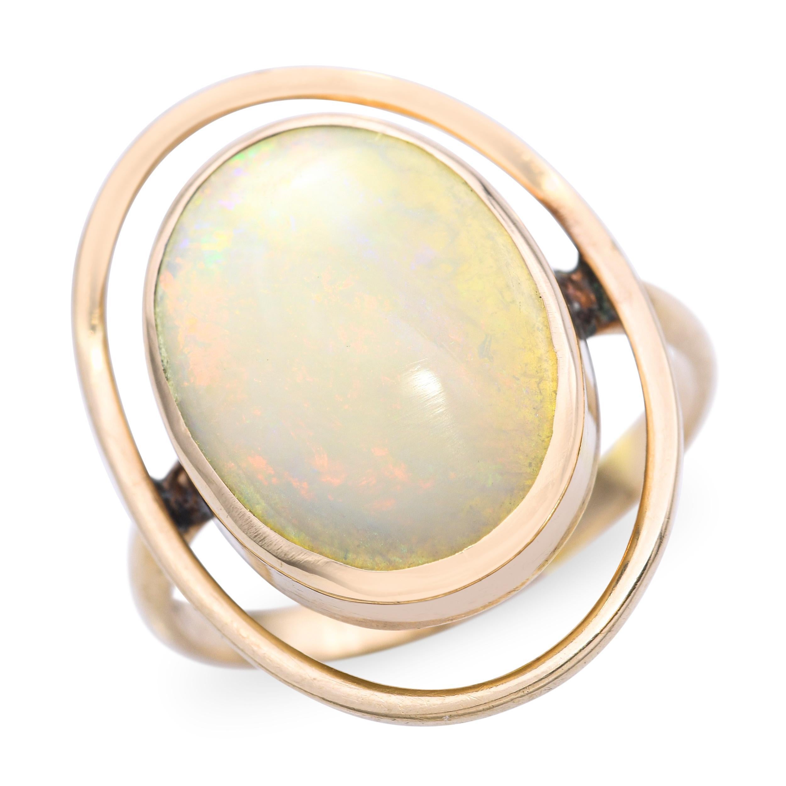 Cette bague vintage est réalisée en or jaune 14k et met en valeur une opale naturelle lumineuse comme pièce maîtresse. L'opale présente un jeu de couleurs captivant, avec des éclats de vert, de bleu et de rose qui se déplacent magnifiquement dans la